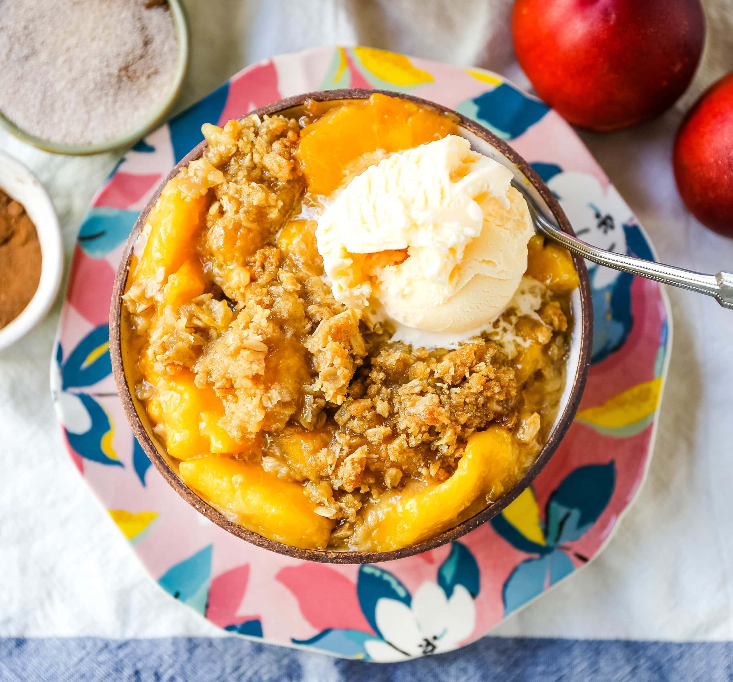 Peach Crisp. Fresh sweetened peaches with a brown sugar oat crumble topping with creamy vanilla ice cream. The perfect summer dessert! www.modernhoney.com #peach #peaches #peachcrisp #peachrecipes #peachdessert