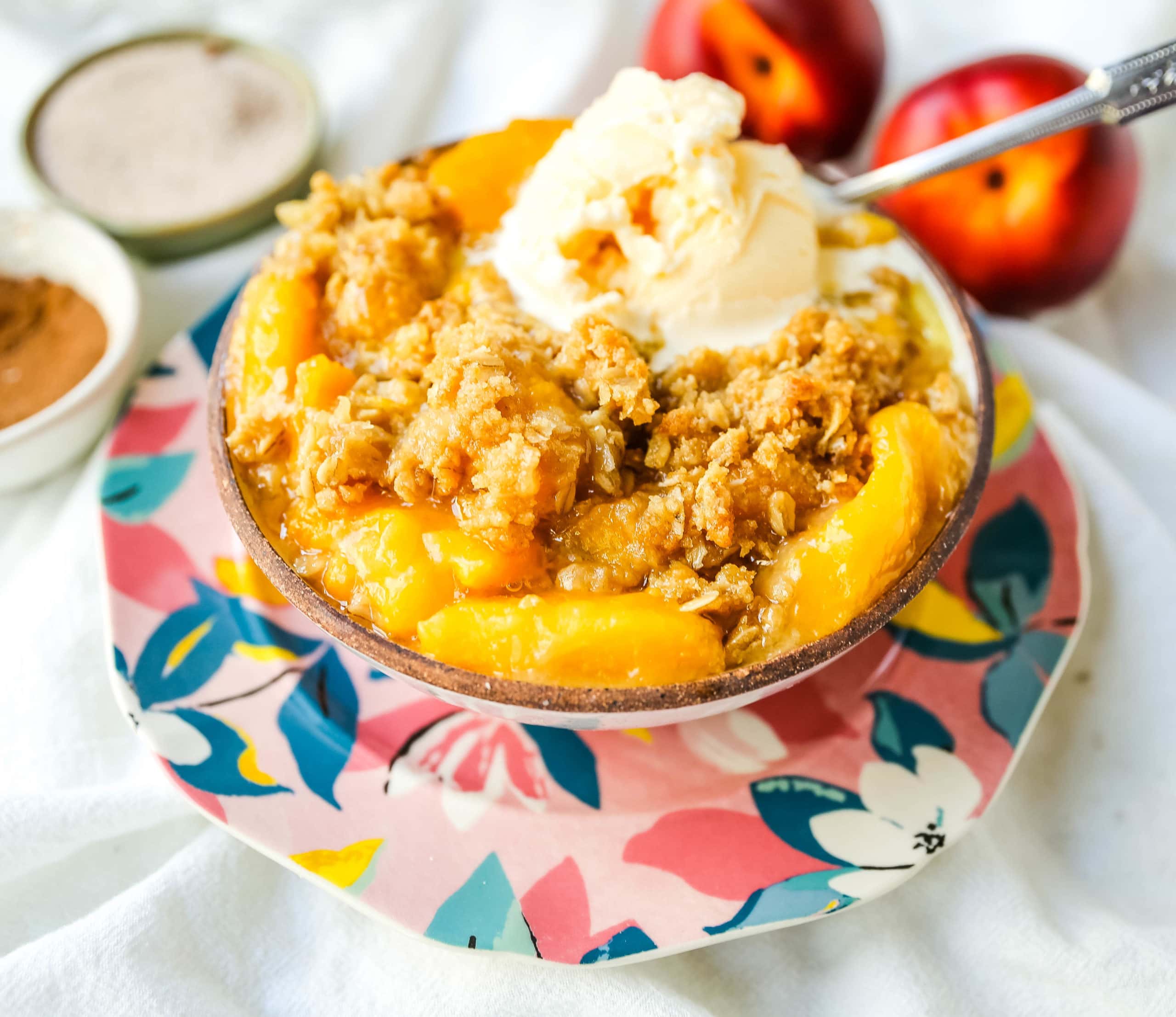 Peach Crisp. Fresh sweetened peaches with a brown sugar oat crumble topping with creamy vanilla ice cream. The perfect summer dessert! www.modernhoney.com #peach #peaches #peachcrisp #peachrecipes #peachdessert