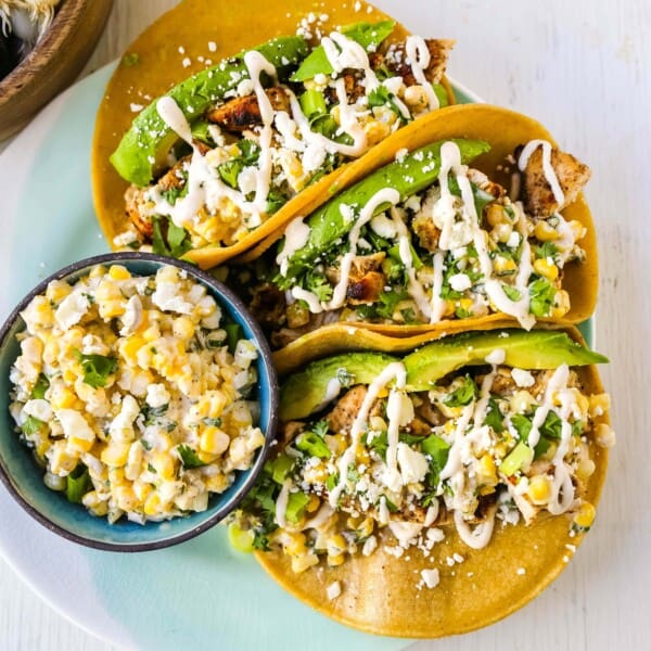 Mexican Street Corn Chicken Tacos Marinated grilled chicken with a homemade street corn salsa, fresh avocado, cotija cheese, and spiced Mexican crema. These tacos will become a family favorite in no time at all! www.modernhoney.com #taco #tacos #mexicanfood #chickentacos