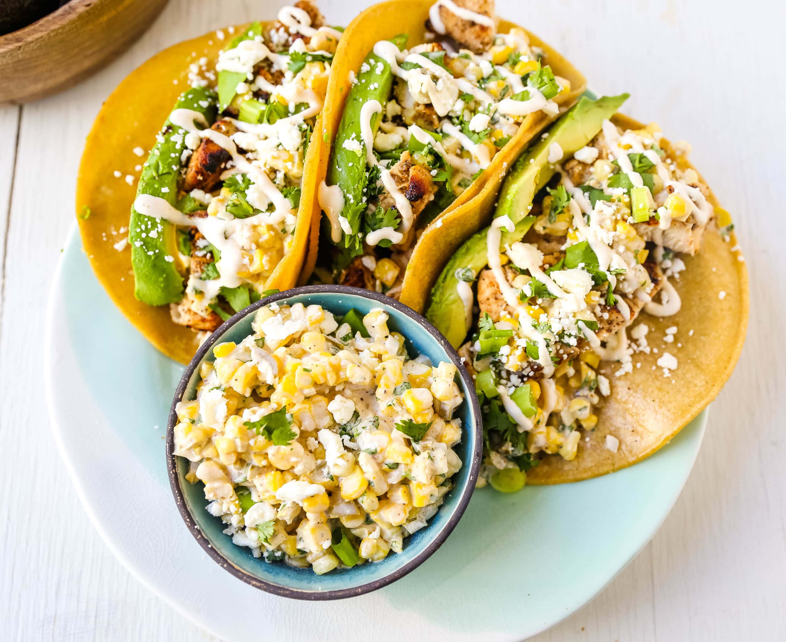 Mexican Street Corn Chicken Tacos Marinated grilled chicken with a homemade street corn salsa, fresh avocado, cotija cheese, and spiced Mexican crema. These tacos will become a family favorite in no time at all! www.modernhoney.com #taco #tacos #mexicanfood #chickentacos