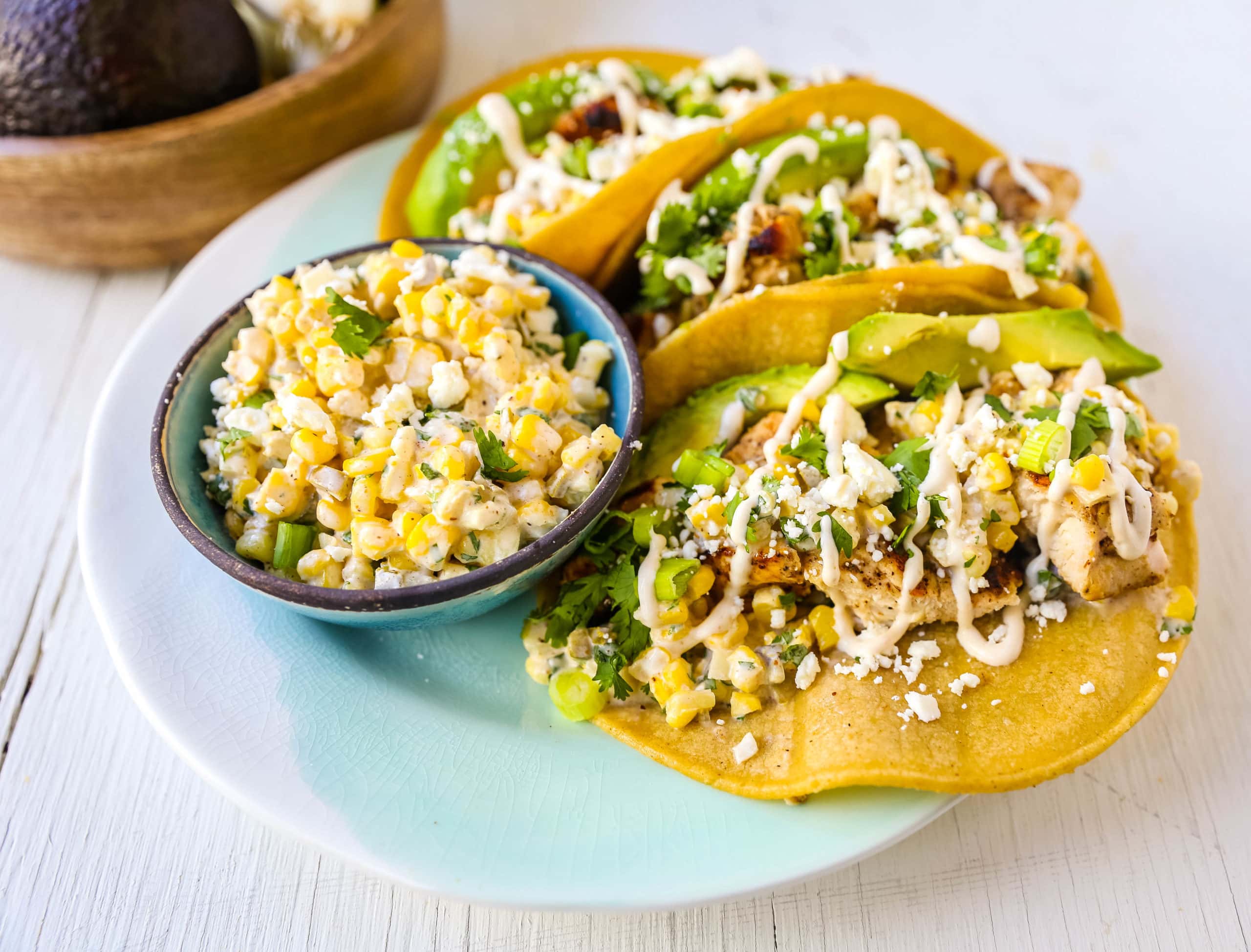 Mexican Street Corn Chicken Tacos Marinated grilled chicken with a homemade street corn salsa, fresh avocado, cotija cheese, and spiced Mexican crema. These tacos will become a family favorite in no time at all! www.modernhoney.com #taco #tacos #mexicanfood #chickentacos