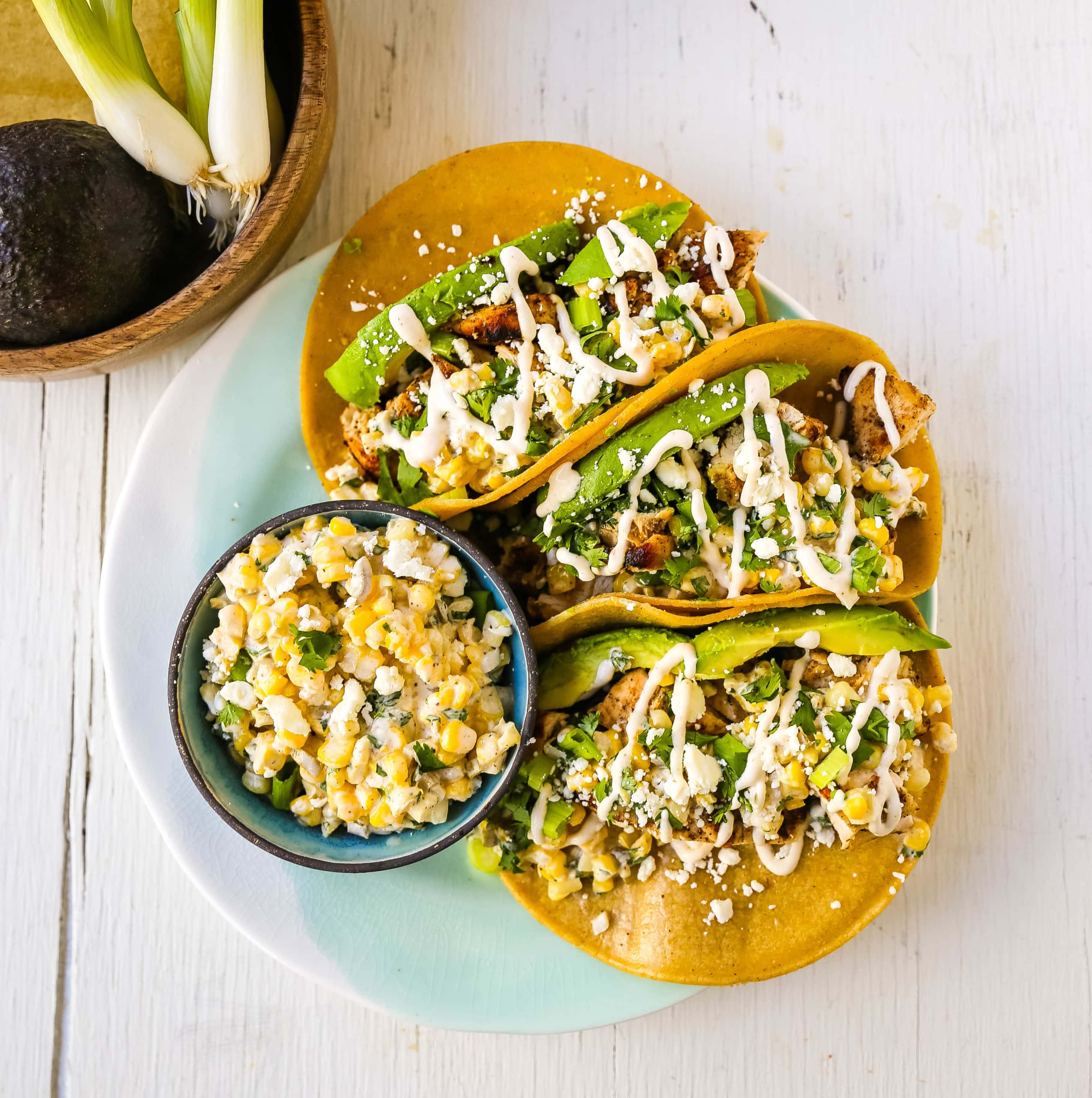 Mexican Street Corn Chicken Tacos Marinated grilled chicken with a homemade street corn salsa, fresh avocado, cotija cheese, and spiced Mexican crema. These tacos will become a family favorite in no time at all! www.modernhoney.com #taco #tacos #mexicanfood #chickentacos