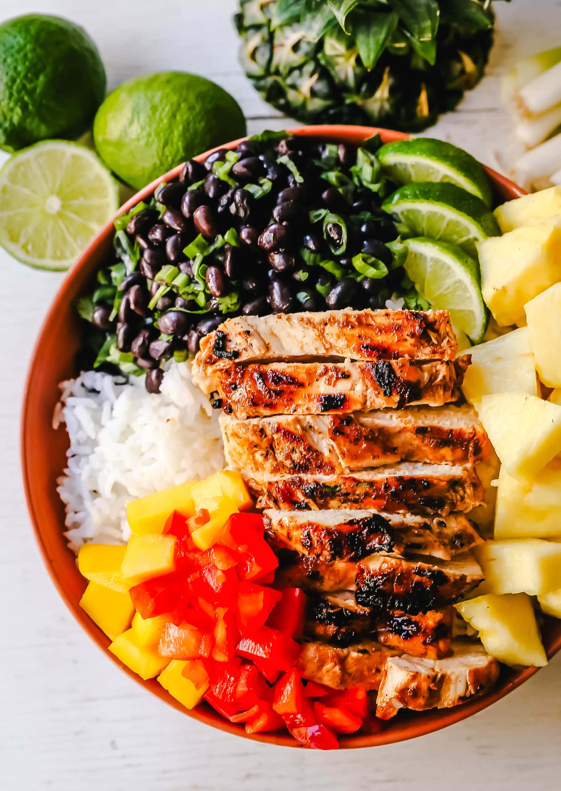 Jerk Chicken Bowl Jamaican spiced grilled Jerk Chicken with rice, black beans, cilantro, fresh pineapple and mango, and red peppers. www.modernhoney.com #jerkchicken #chicken #chickenbowl