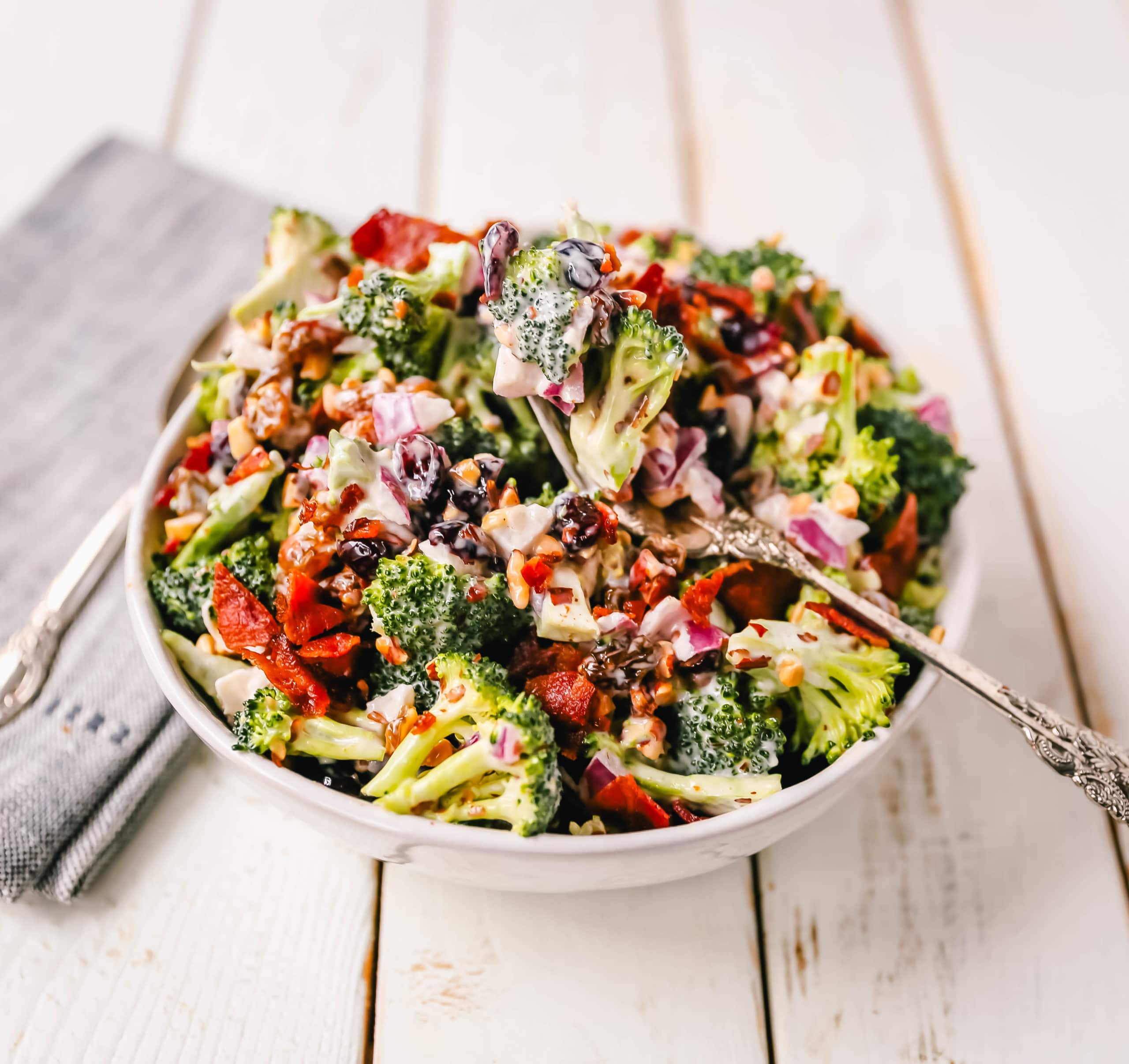Broccoli Salad. Crunchy broccoli salad with crispy bacon, sweet dried cranberries, onion, nuts, tossed in a sweet and tangy dressing. A classic potluck side dish recipe! www.modernhoney.com #broccolisalad #sidedish #potluck #sides
