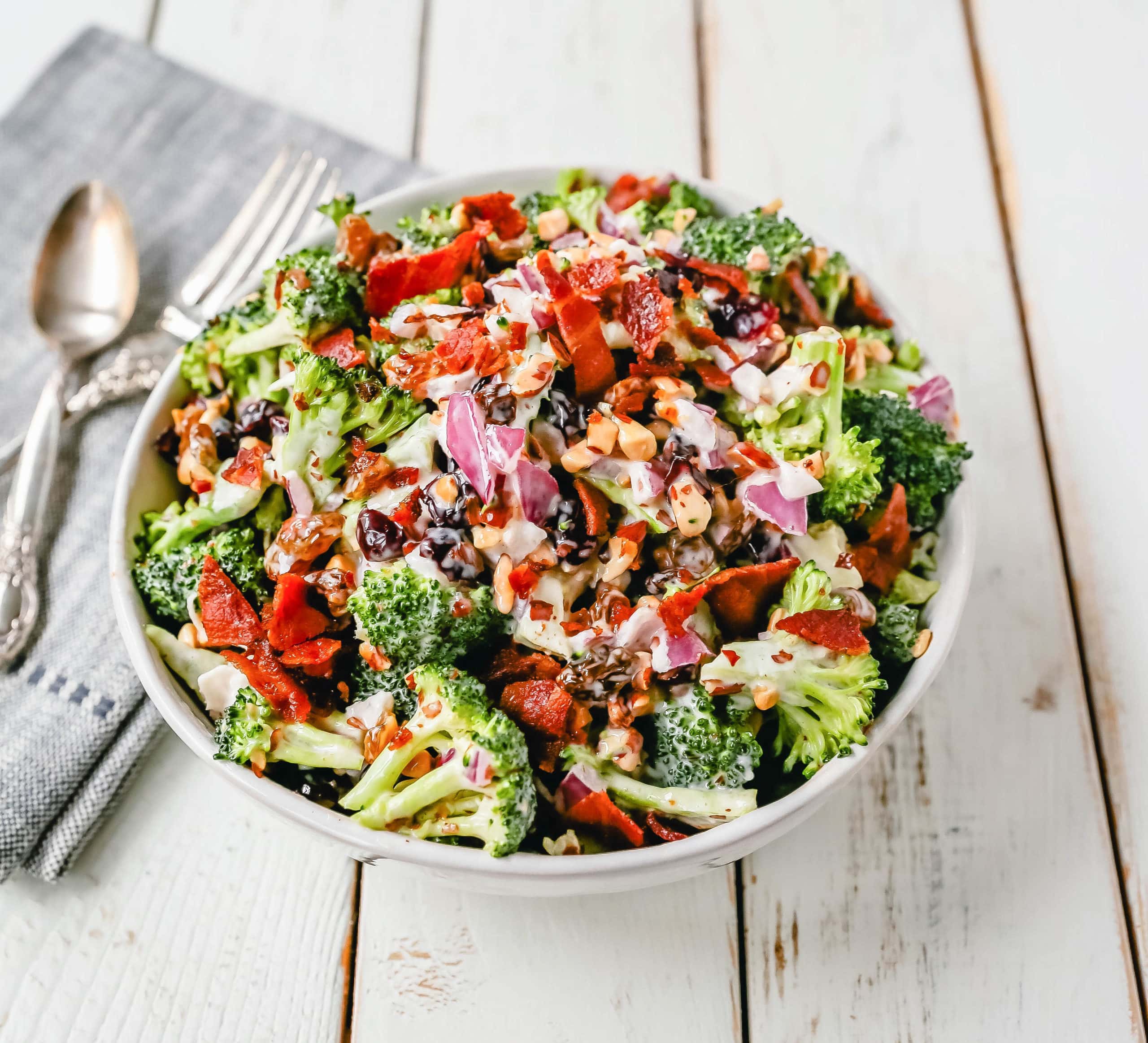 Broccoli Salad. Crunchy broccoli salad with crispy bacon, sweet dried cranberries, onion, nuts, tossed in a sweet and tangy dressing. A classic potluck side dish recipe! www.modernhoney.com #broccolisalad #sidedish #potluck #sides