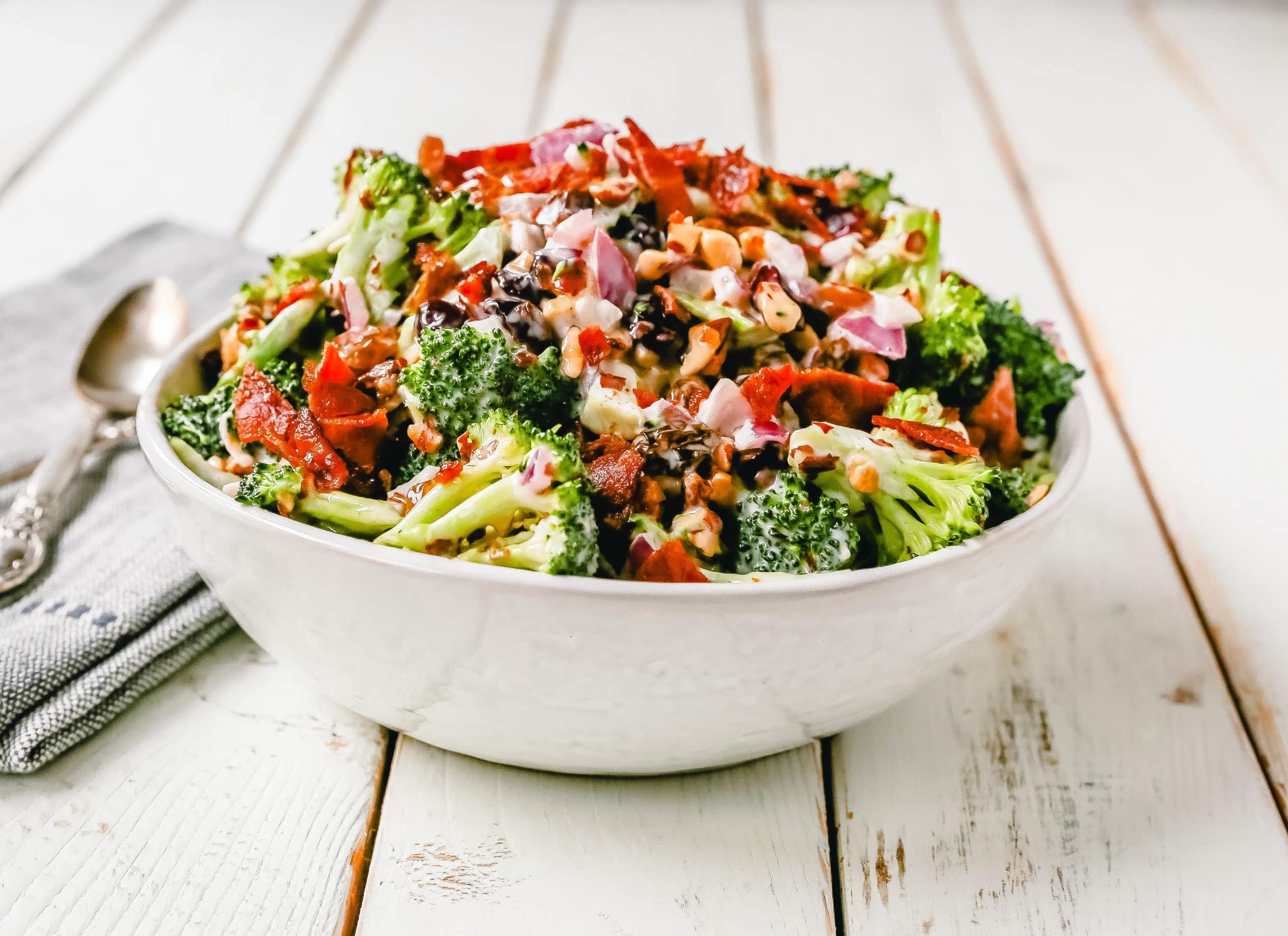 Broccoli Salad. Crunchy broccoli salad with crispy bacon, sweet dried cranberries, onion, nuts, tossed in a sweet and tangy dressing. A classic potluck side dish recipe! www.modernhoney.com #broccolisalad #sidedish #potluck #sides