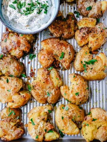 Crispy Smashed Potatoes. Crispy smashed potatoes with creamy, fluffy centers and crispy outsides. Petite potatoes topped with olive oil, salted butter, salt, and pepper and baked until crispy and topped with a garlic cheddar sour cream dip. The best smashed potatoes recipe!
