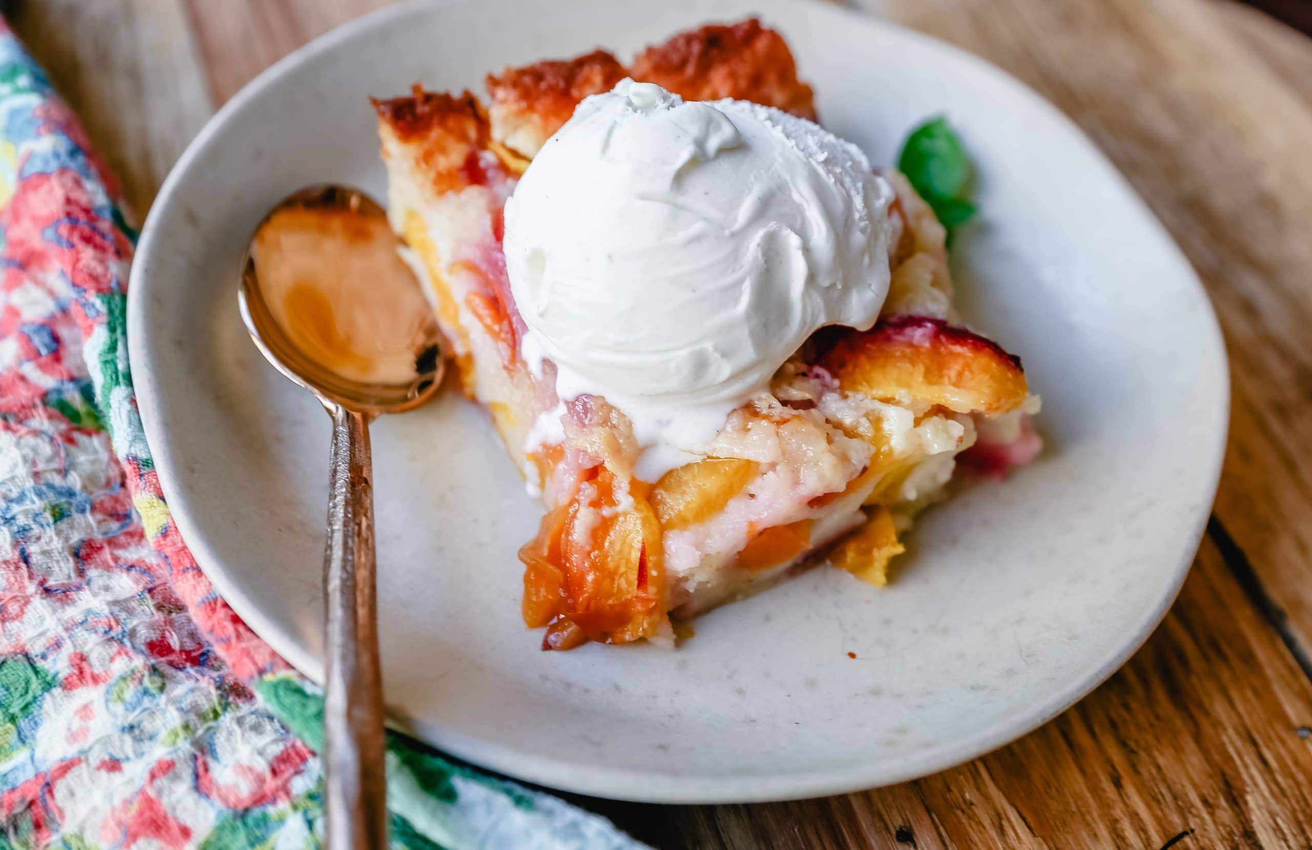 Texas Style Peach Cobbler. Fresh peaches sweetened with sugar and topped with a creamy buttery cake-like topping. A Texas favorite dessert!  #peaches #peachdessert #peachcobbler