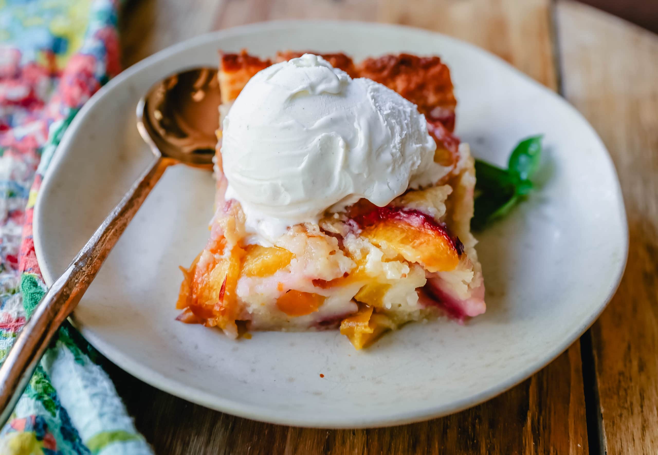 Texas Style Peach Cobbler. Fresh peaches sweetened with sugar and topped with a creamy buttery cake-like topping. A Texas favorite dessert!  #peaches #peachdessert #peachcobbler