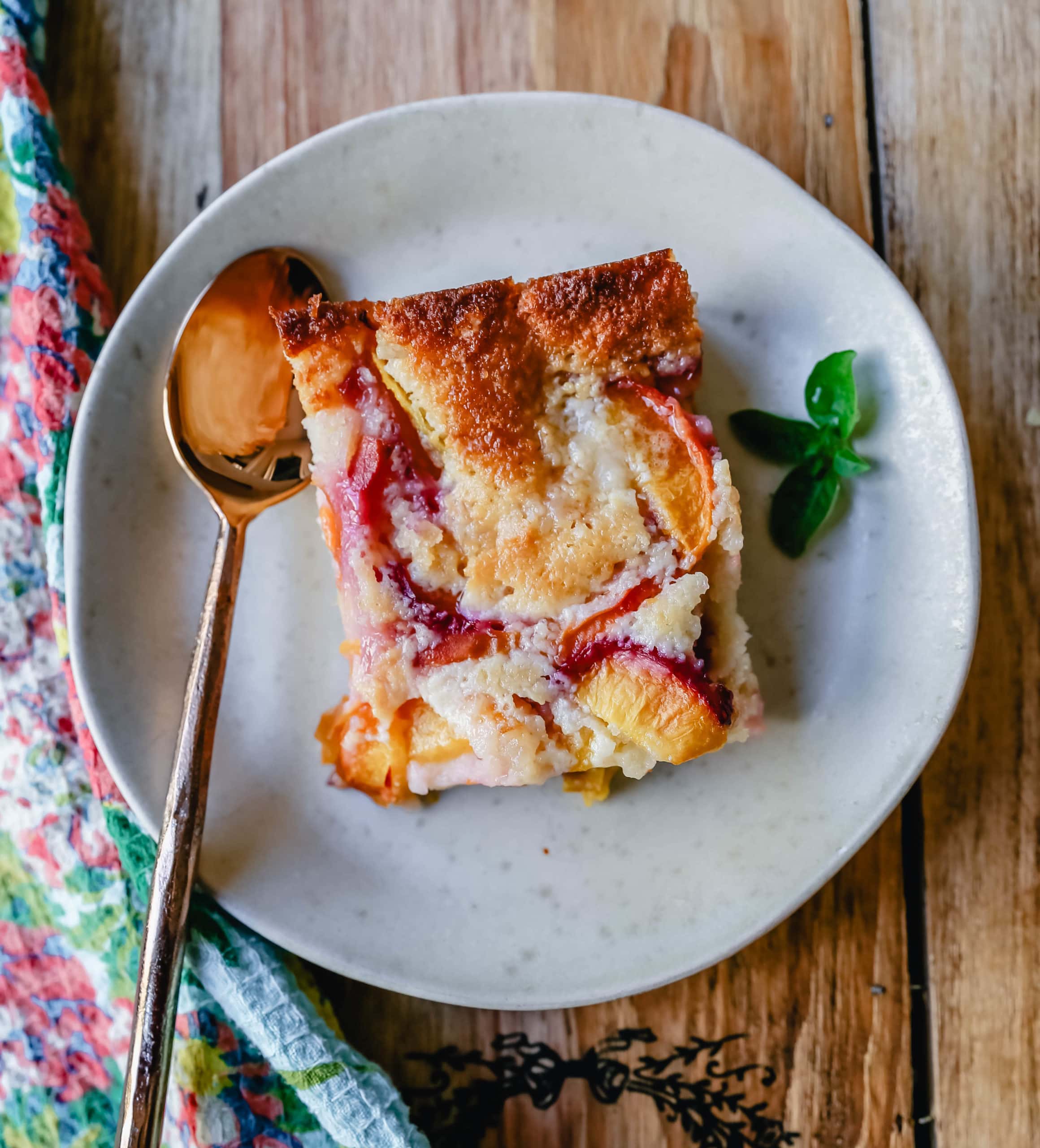 Texas Style Peach Cobbler. Fresh peaches sweetened with sugar and topped with a creamy buttery cake-like topping. A Texas favorite dessert!  #peaches #peachdessert #peachcobbler