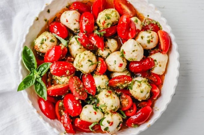 Pesto Caprese Salad. Fresh cherry or grape tomatoes, vibrant pesto sauce, creamy fresh mozzarella balls, extra-virgin olive oil, balsamic glaze, basil, and spices. A perfect summer salad recipe!