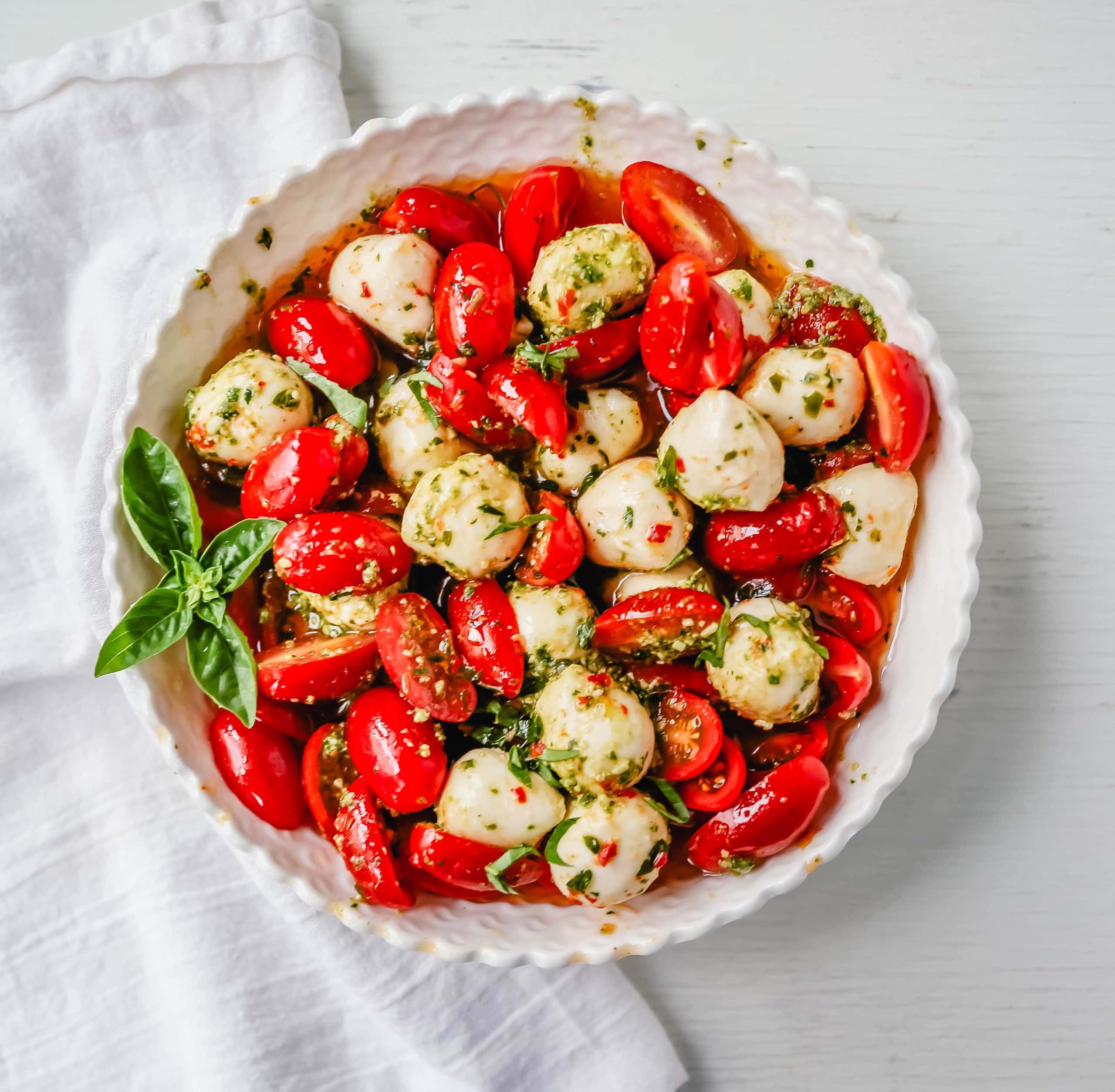 Pesto Caprese Salad. Fresh cherry or grape tomatoes, vibrant pesto sauce, creamy fresh mozzarella balls, extra-virgin olive oil, balsamic glaze, basil, and spices. A perfect summer salad recipe!