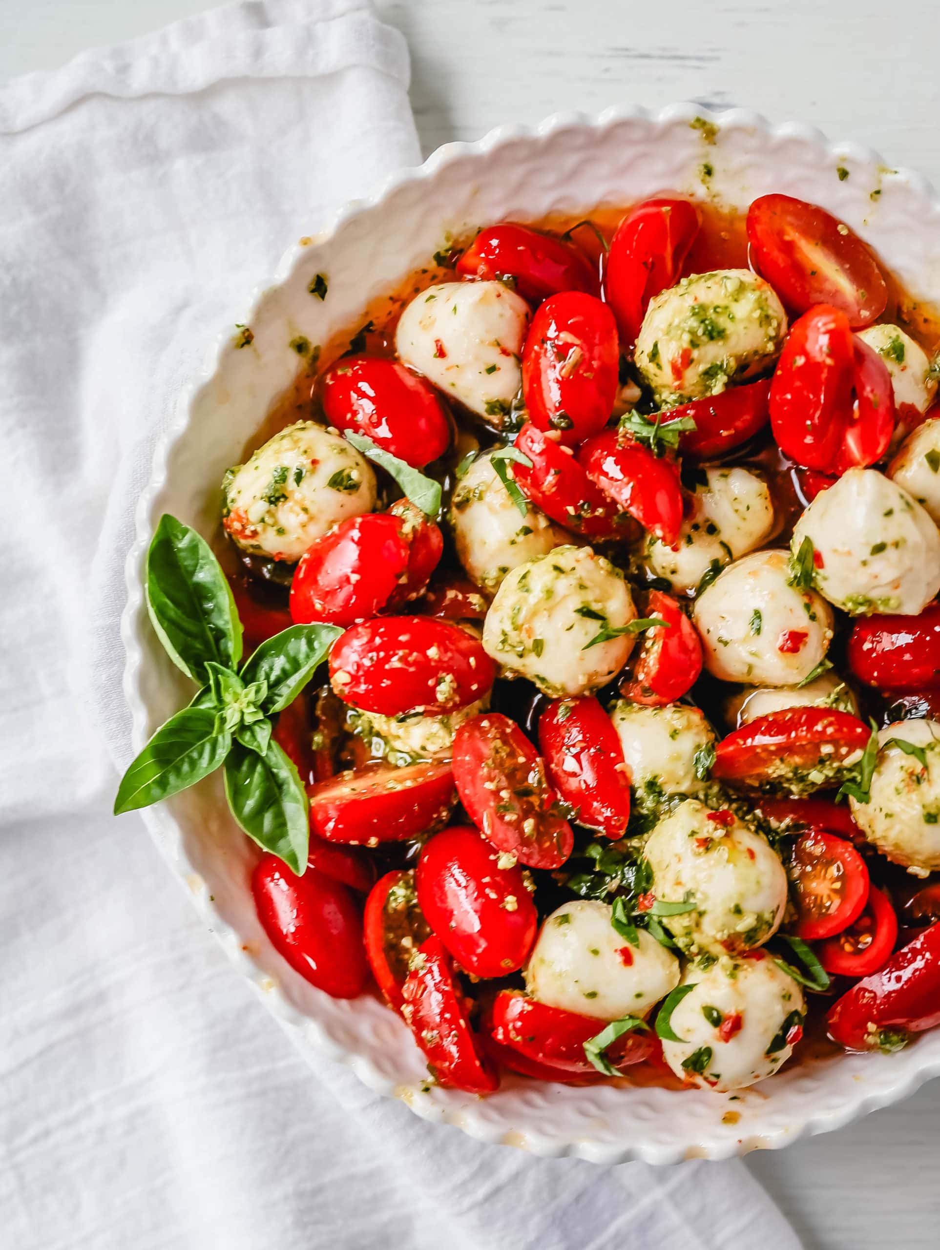 Pesto Caprese Salad. Fresh cherry or grape tomatoes, vibrant pesto sauce, creamy fresh mozzarella balls, extra-virgin olive oil, balsamic glaze, basil, and spices. A perfect summer salad recipe!