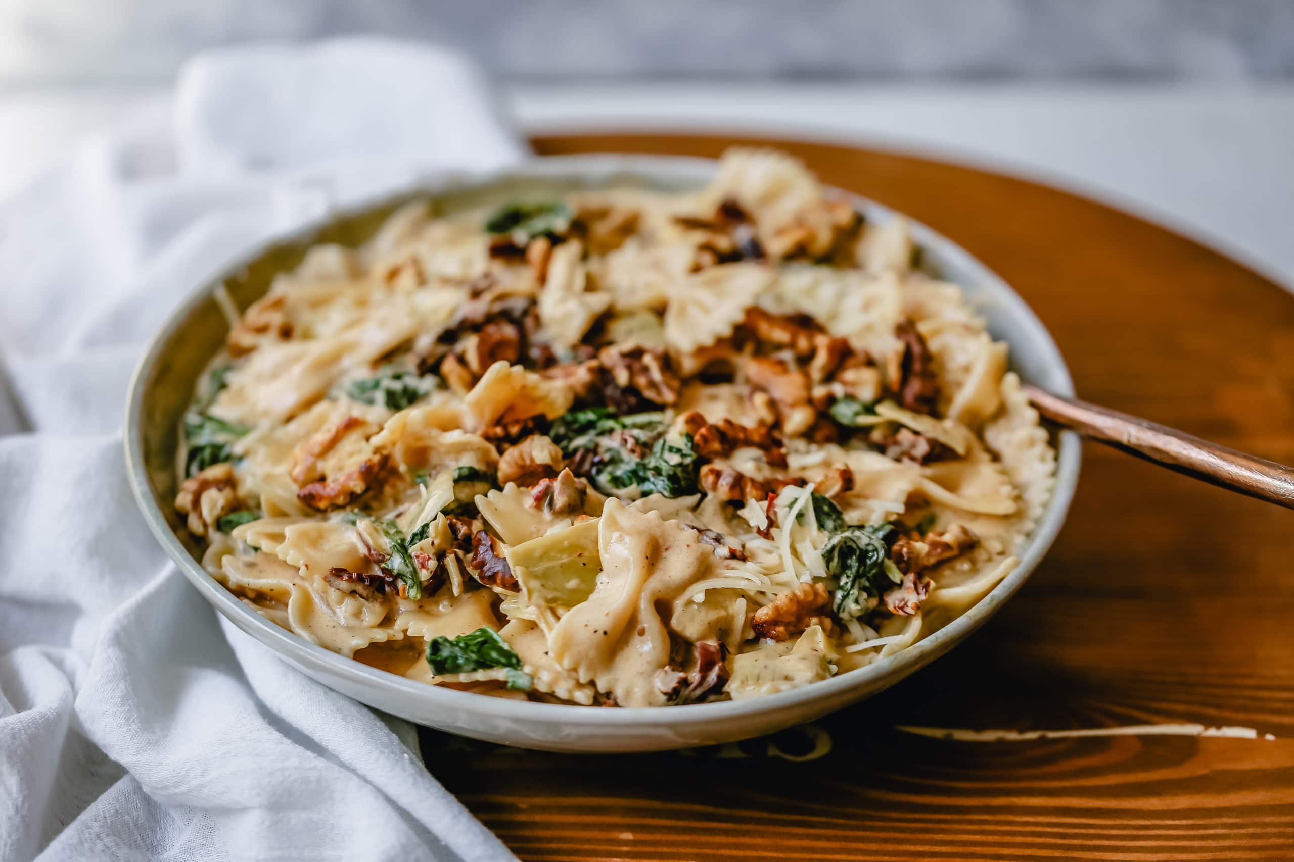 Creamy Bowtie Pasta with Sundried Tomatoes Bowtie Pasta tossed with a garlic sundried tomato cream sauce with artichoke hearts and parmesan cheese and crunchy toasted walnuts. A quick 20-minute weeknight meal. #pasta #dinner