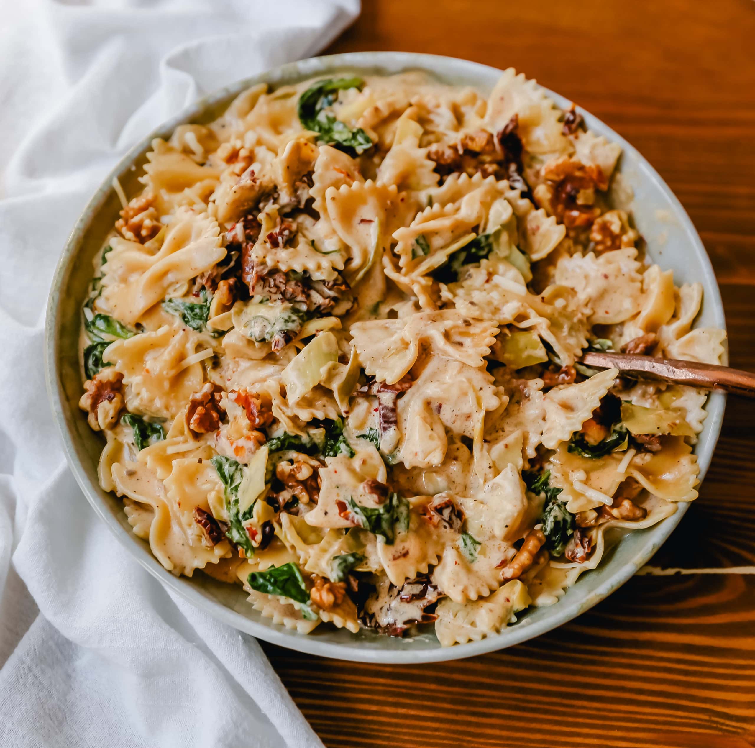 Creamy Bowtie Pasta with Sundried Tomatoes Bowtie Pasta tossed with a garlic sundried tomato cream sauce with artichoke hearts and parmesan cheese and crunchy toasted walnuts. A quick 20-minute weeknight meal. #pasta #dinner