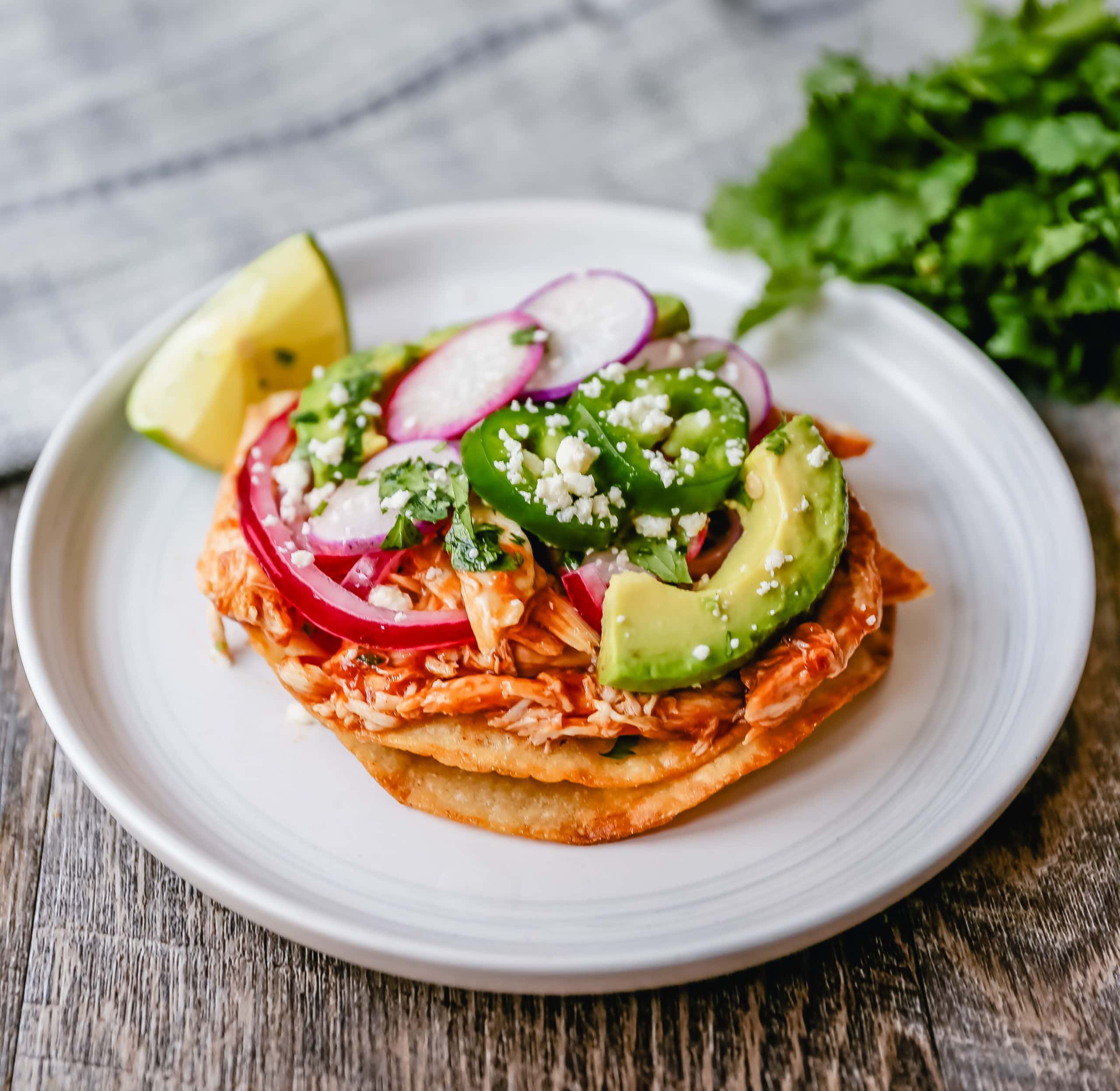 Chicken Tostadas Chile Chicken Tostadas made with homemade tostada shells topped with chile spiced chicken topped with cotija cheese, cilantro, pickled red onion, fresh avocado, and jalapeños.