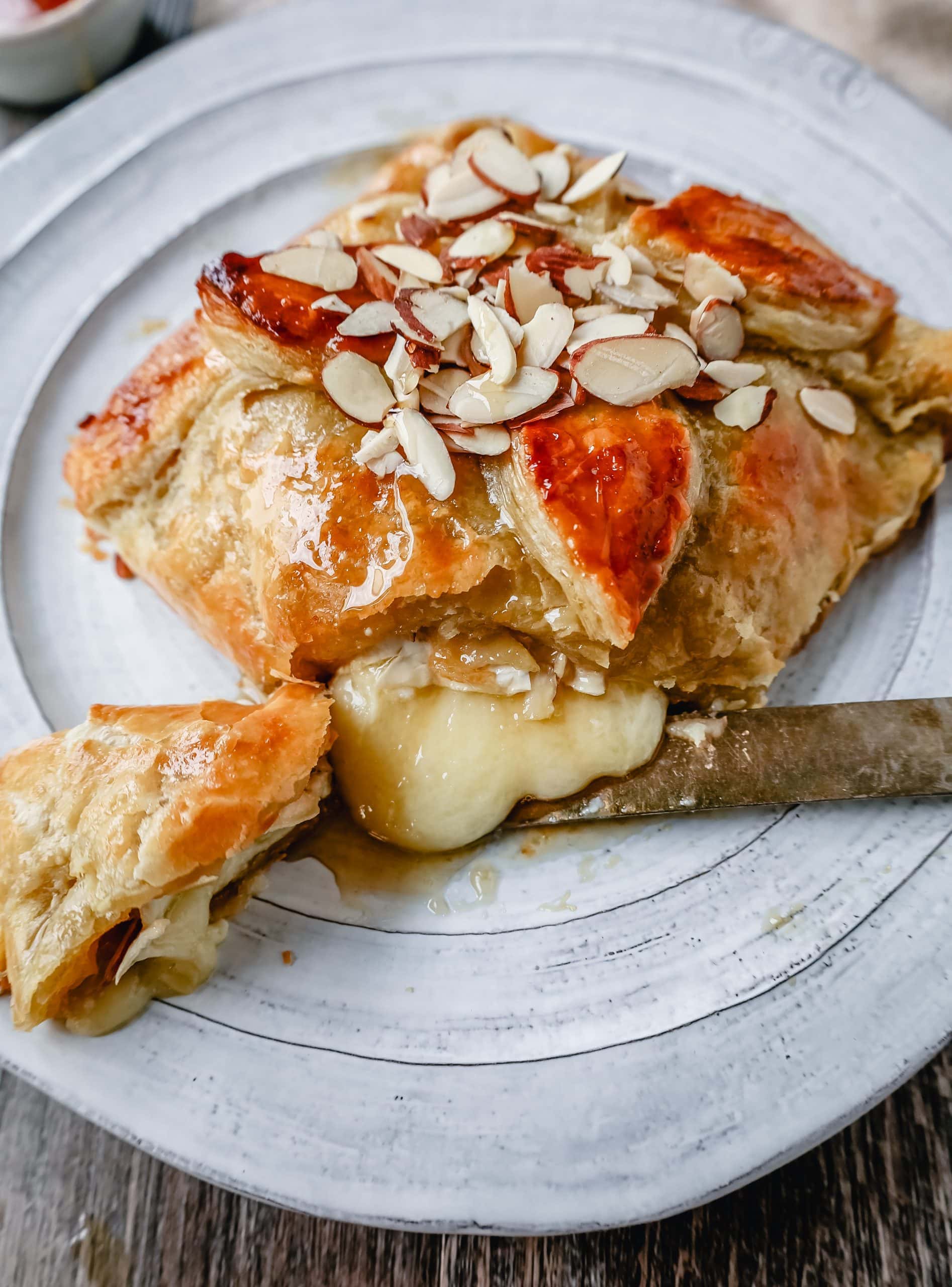 Honey Almond Puff Pastry Wrapped Brie Brie cheese wrapped in buttery puff pastry with local honey and sliced almonds. This is a sweet and salty festive party appetizer.