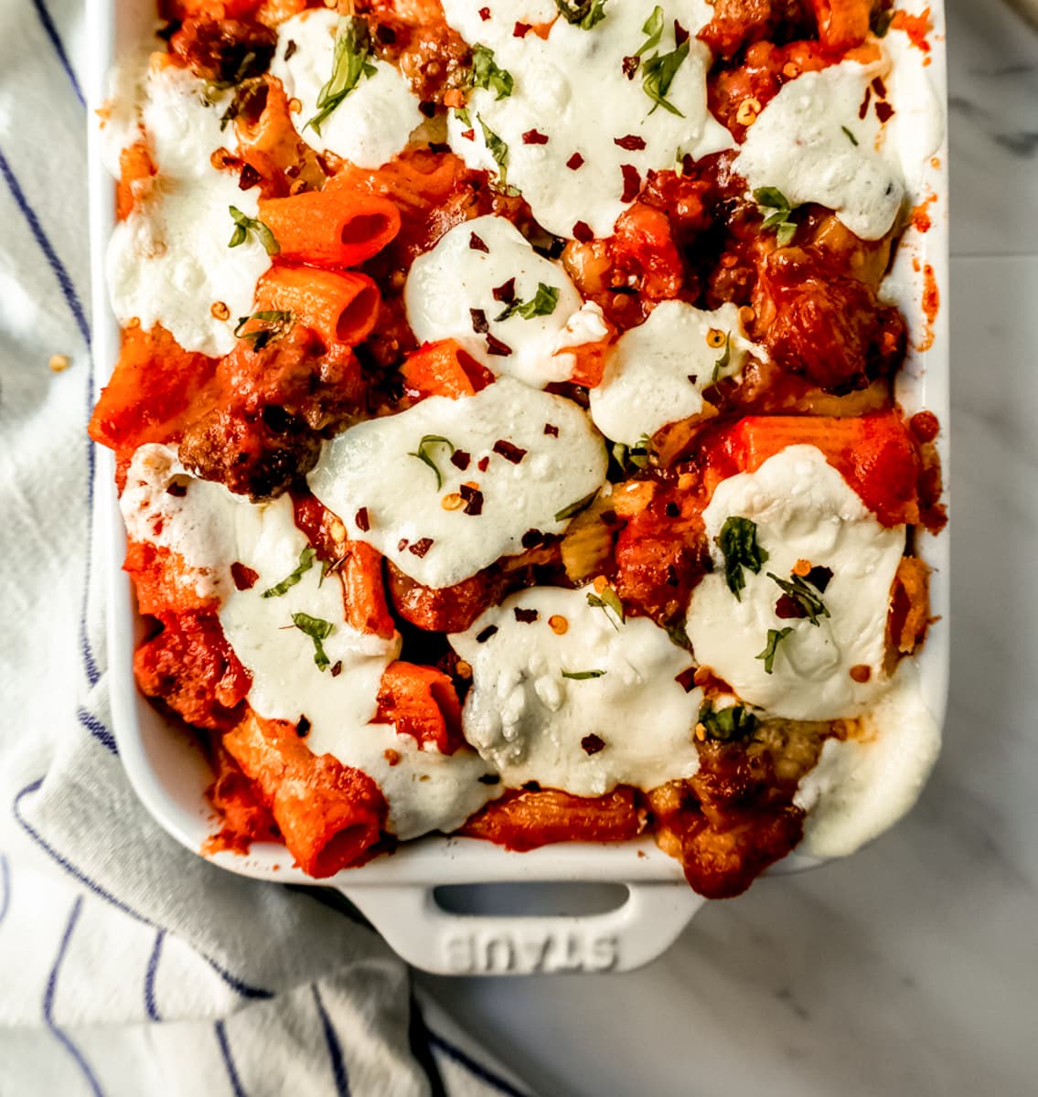 This Baked Ziti Pasta is made with ziti noodles, sausage, marinara sauce, fresh basil, spices, whole milk mozzarella cheese, parmesan cheese, and heavy cream and baked until the cheese is melted. The best-baked ziti recipe! This is a perfect recipe to freeze or make ahead of time.