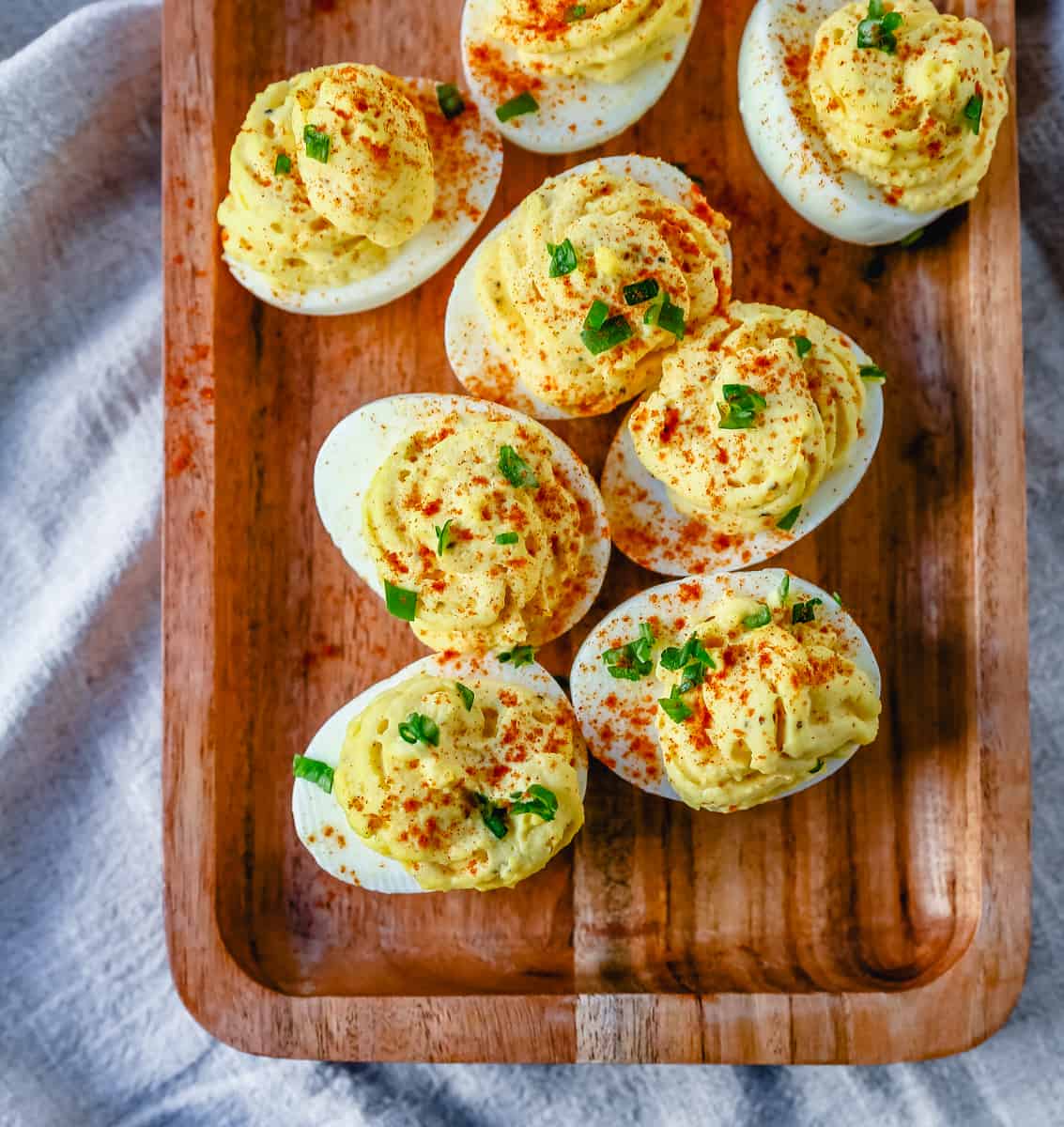 These easy deviled eggs are made with hard-boiled eggs, mayonnaise, mustard, pickle juice, a touch of sugar, a pinch of salt, and pepper, and sprinkled with paprika.