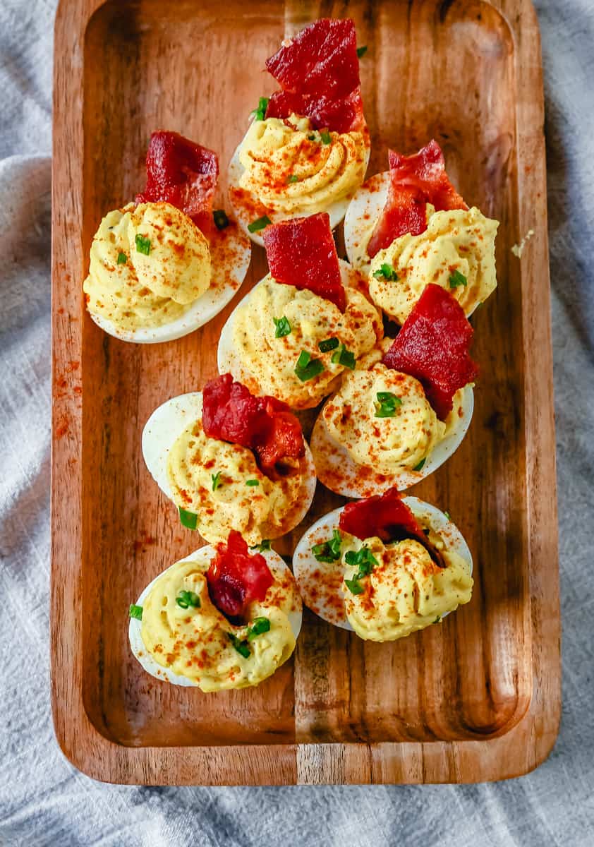 These easy deviled eggs are made with hard-boiled eggs, mayonnaise, mustard, pickle juice, a touch of sugar, a pinch of salt, and pepper, and sprinkled with paprika.