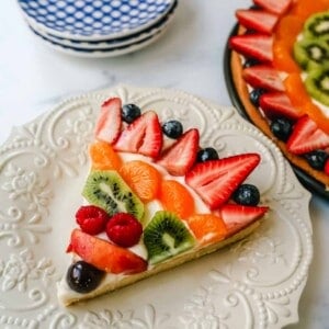 Fruit Pizza with a Sugar Cookie Crust is made with a large, pizza-sized baked sugar cookie and topped with a sweet cream cheese whipped cream and sprinkled with glazed fresh fruit. 