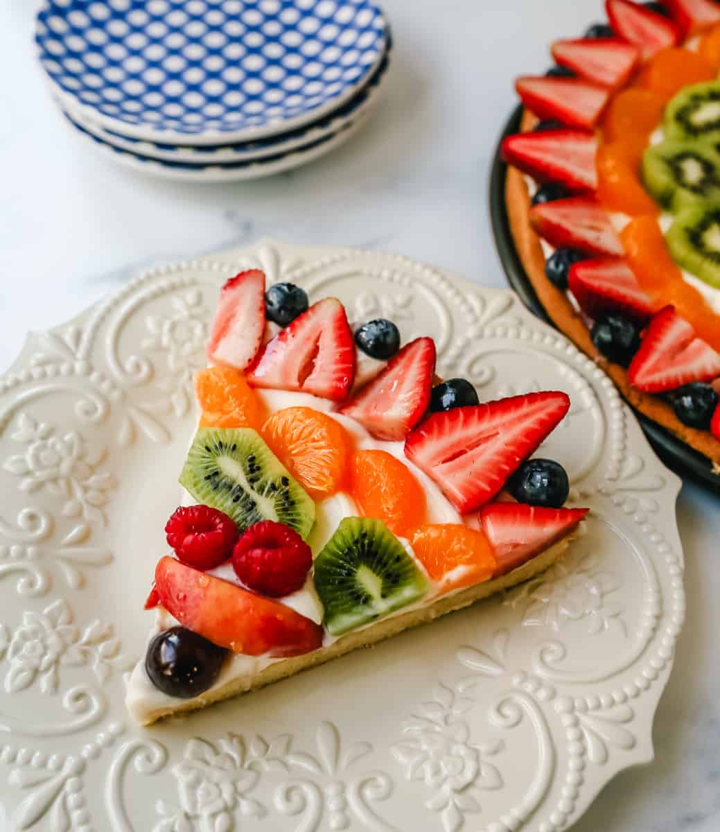 Fruit Pizza with a Sugar Cookie Crust is made with a large, pizza-sized baked sugar cookie and topped with a sweet cream cheese whipped cream and sprinkled with glazed fresh fruit. 