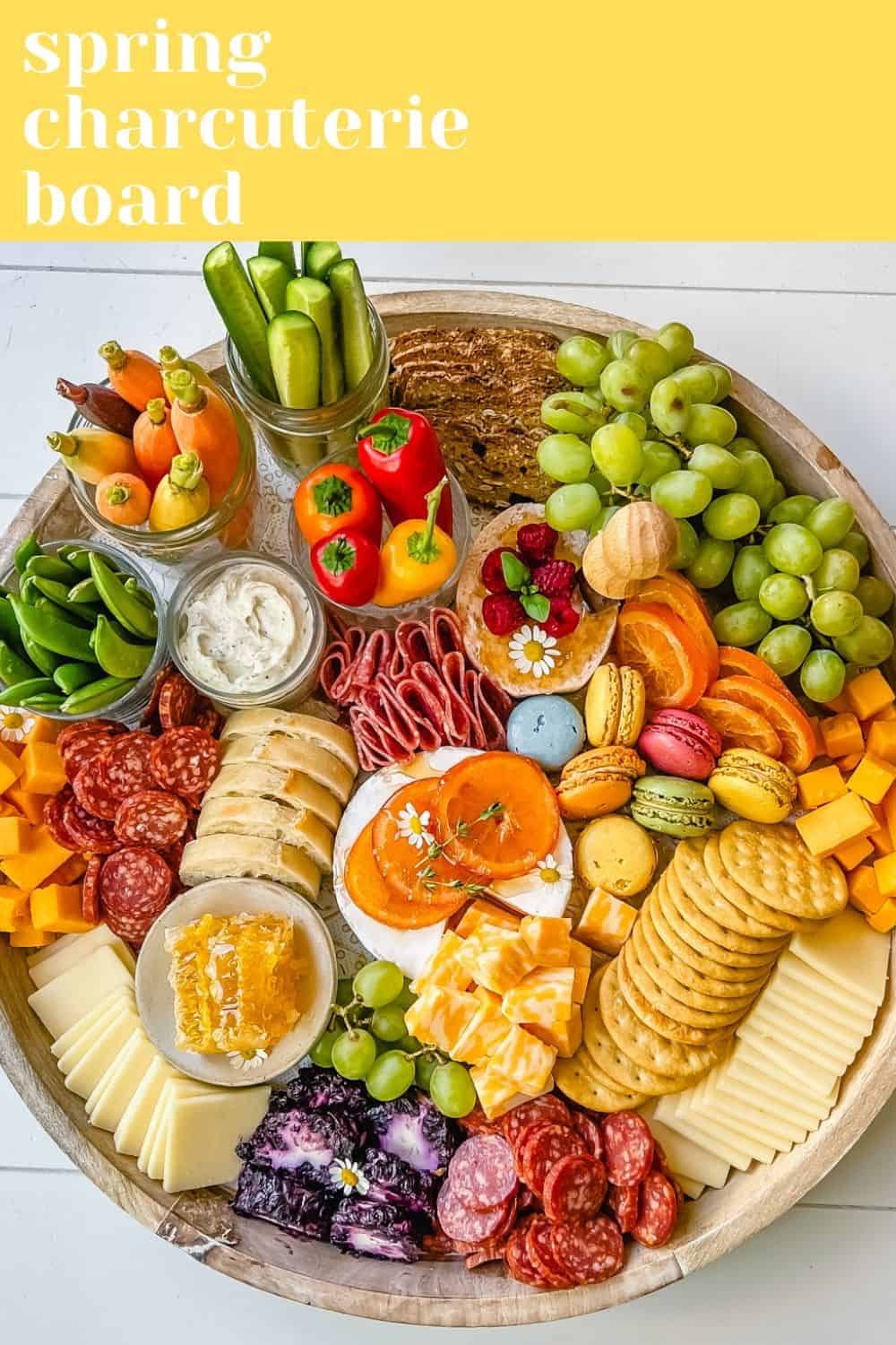 A beautiful Spring Charcuterie Board with fresh ripe fruits, creamy cheeses, crisp vegetables, cured meats, crackers, French baguette slices, honeycomb, macarons, and edible flowers. This is a perfect Spring entertaining board.
