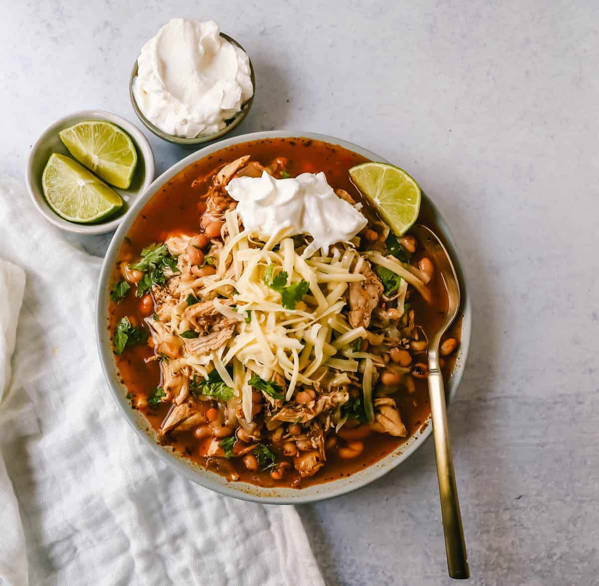 This quick and easy chicken chili is made in less than 30 minutes and filled with protein, good fats, and healthy carbs! This White Chicken Chili is a quick and easy soup recipe made with shredded chicken, onion, garlic, chili powder, green chilies, white beans, and ranch powder, and topped with cheese and sour cream.