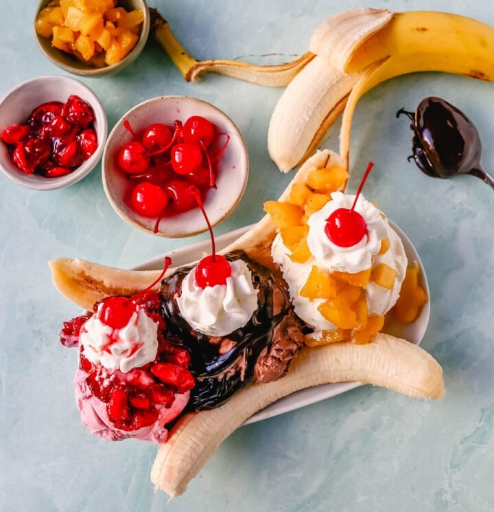 A classic Banana Split recipe made with fresh bananas, chocolate ice cream with hot fudge sauce, strawberry ice cream with strawberry sauce, vanilla ice cream with pineapple sauce, whipped cream, and cherry. 