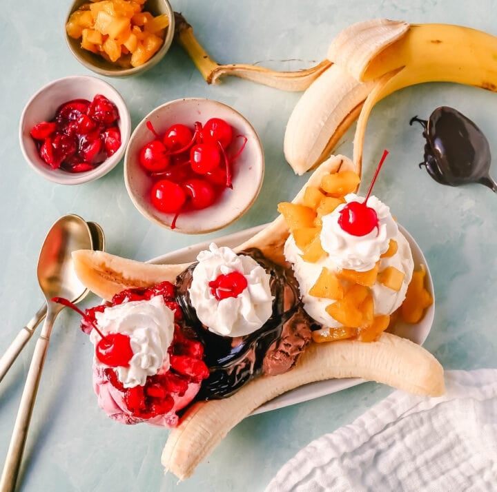 A classic Banana Split recipe made with fresh bananas, chocolate ice cream with hot fudge sauce, strawberry ice cream with strawberry sauce, vanilla ice cream with pineapple sauce, whipped cream, and cherry. 