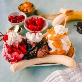 A classic Banana Split recipe made with fresh bananas, chocolate ice cream with hot fudge sauce, strawberry ice cream with strawberry sauce, vanilla ice cream with pineapple sauce, whipped cream, and cherry.