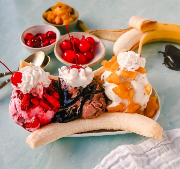 A classic Banana Split recipe made with fresh bananas, chocolate ice cream with hot fudge sauce, strawberry ice cream with strawberry sauce, vanilla ice cream with pineapple sauce, whipped cream, and cherry. 