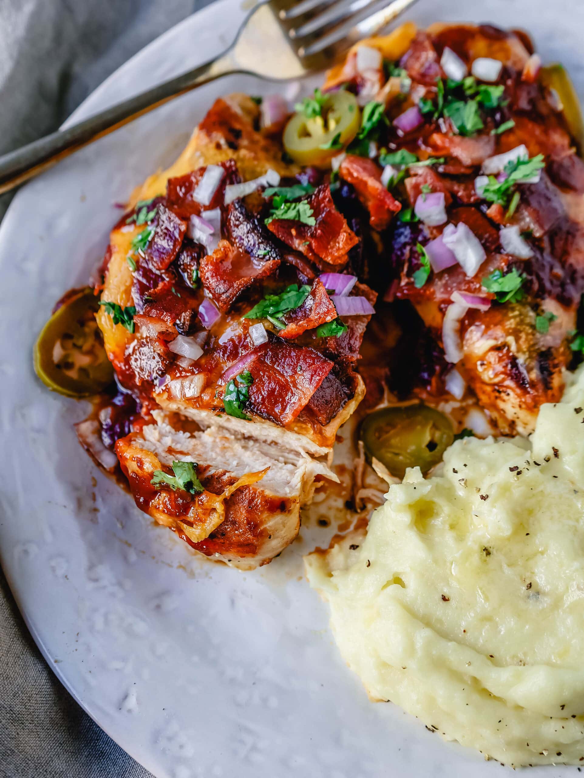 This Cowboy Chicken is Marinated Grilled Chicken topped with BBQ Sauce, Crispy Bacon, and Cheddar Cheese. Top with Fresh Cilantro and Red Onion. This is the best Monterey Chicken recipe!