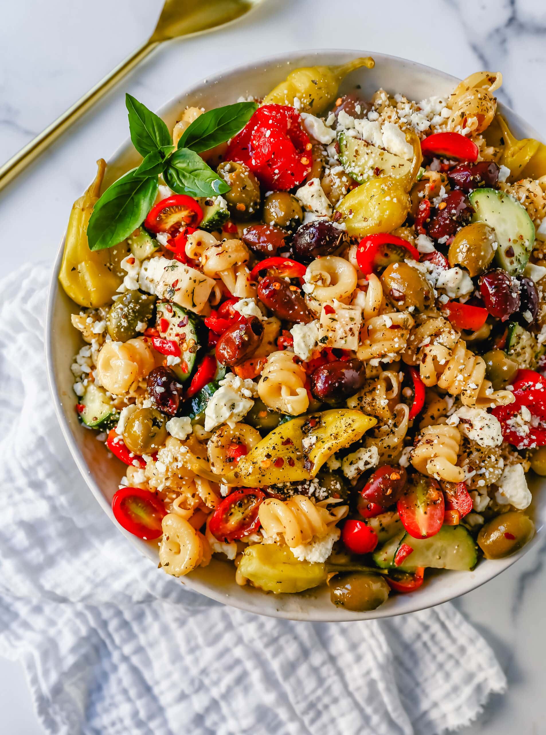 Homemade Greek Pasta Salad made with Pasta, Greek Olives, Feta Cheese, Peppers, Tomatoes, Cucumber, Pepperoncinis, and tossed in a Homemade Greek Dressing. The Best Greek Pasta Salad Recipe!