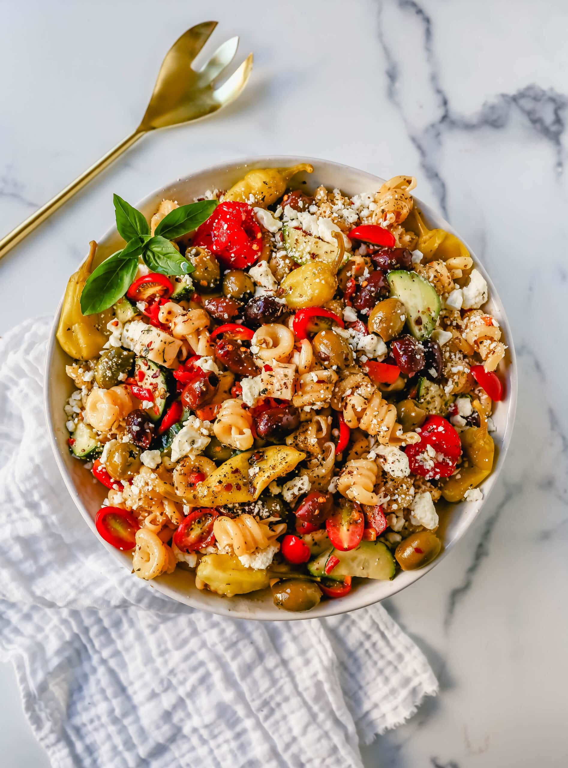 Homemade Greek Pasta Salad made with Pasta, Greek Olives, Feta Cheese, Peppers, Tomatoes, Cucumber, Pepperoncinis, and tossed in a Homemade Greek Dressing. The Best Greek Pasta Salad Recipe!