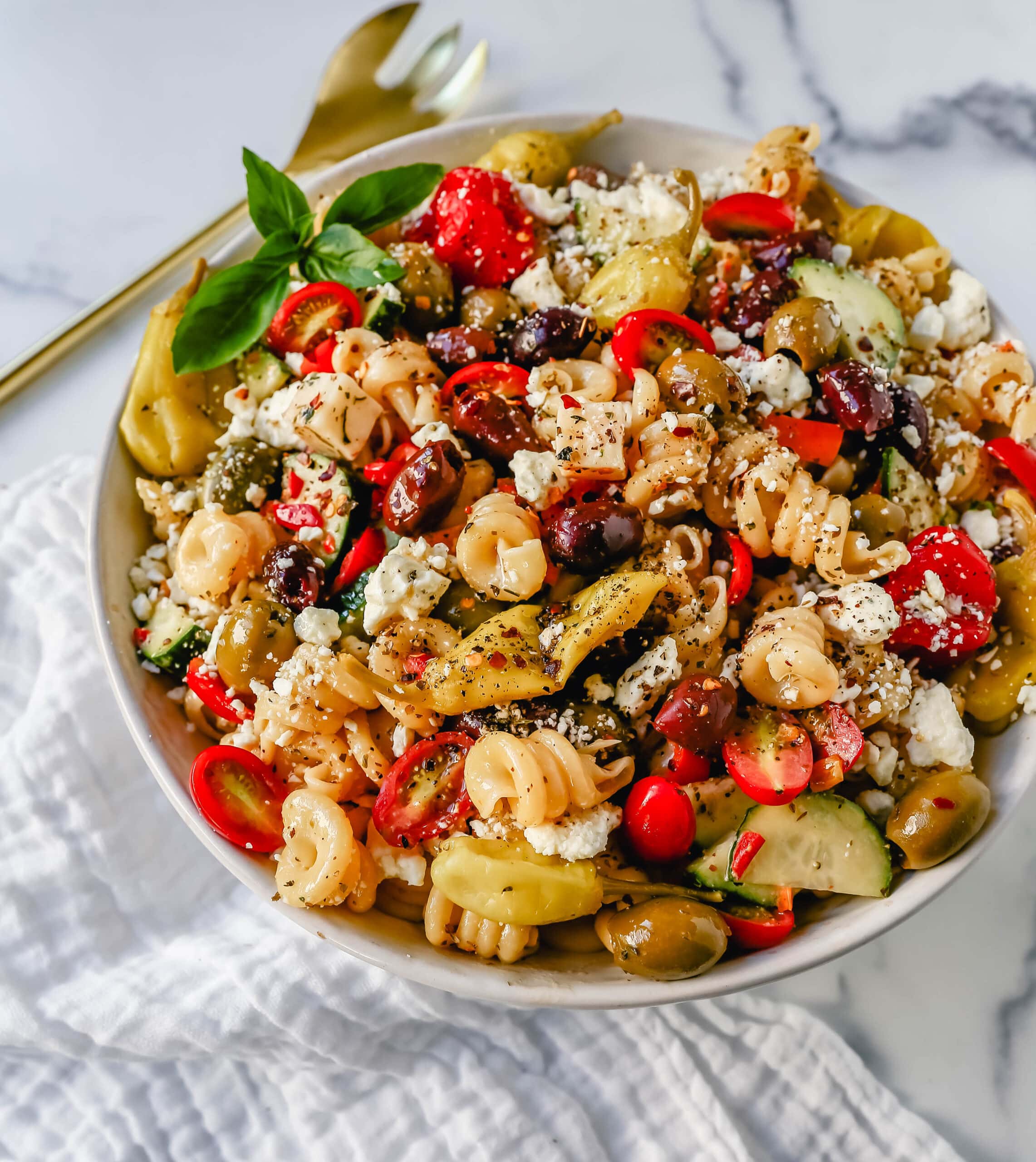 Homemade Greek Pasta Salad made with Pasta, Greek Olives, Feta Cheese, Peppers, Tomatoes, Cucumber, Pepperoncinis, and tossed in a Homemade Greek Dressing. The Best Greek Pasta Salad Recipe!