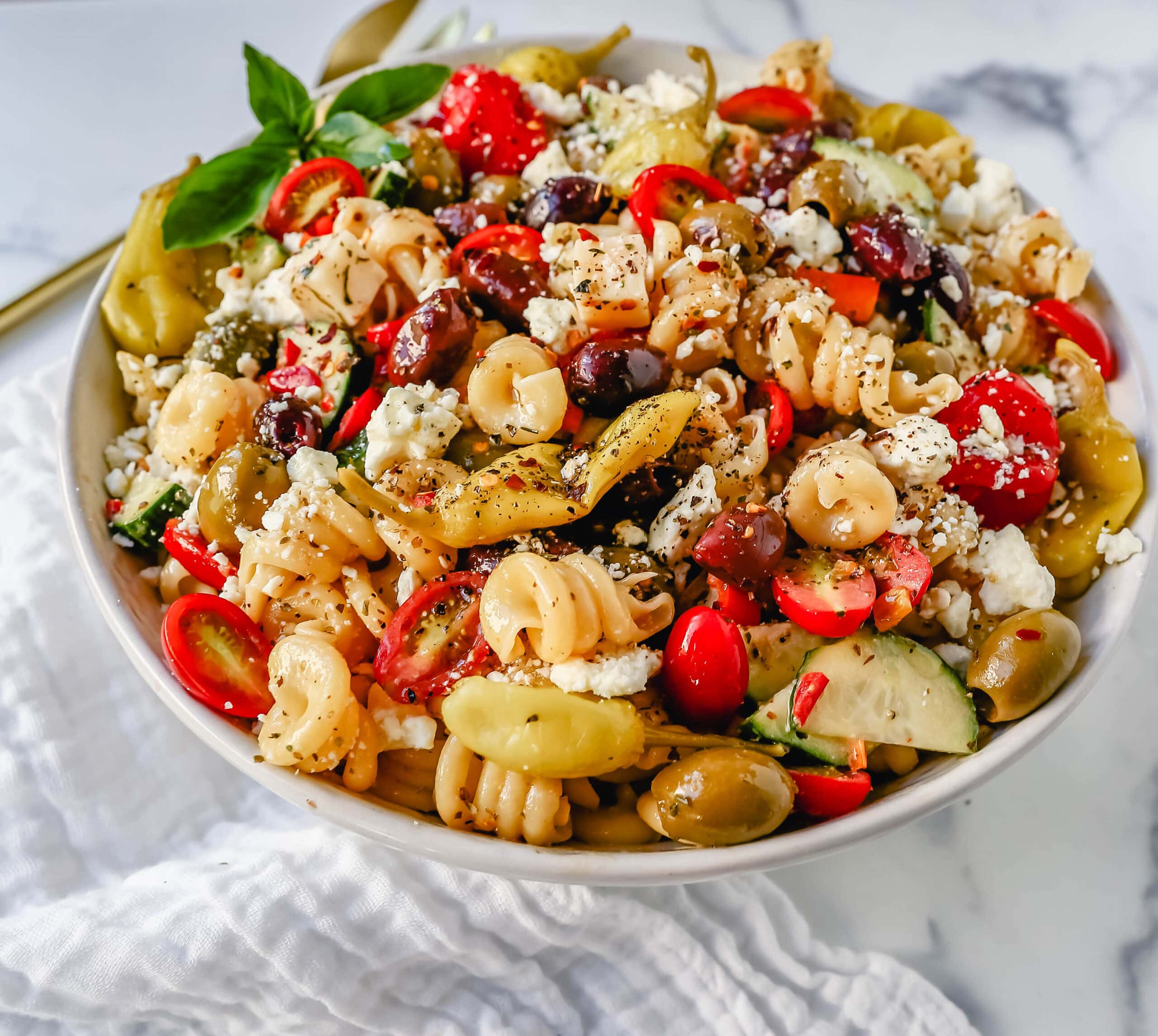 Homemade Greek Pasta Salad made with Pasta, Greek Olives, Feta Cheese, Peppers, Tomatoes, Cucumber, Pepperoncinis, and tossed in a Homemade Greek Dressing. The Best Greek Pasta Salad Recipe!