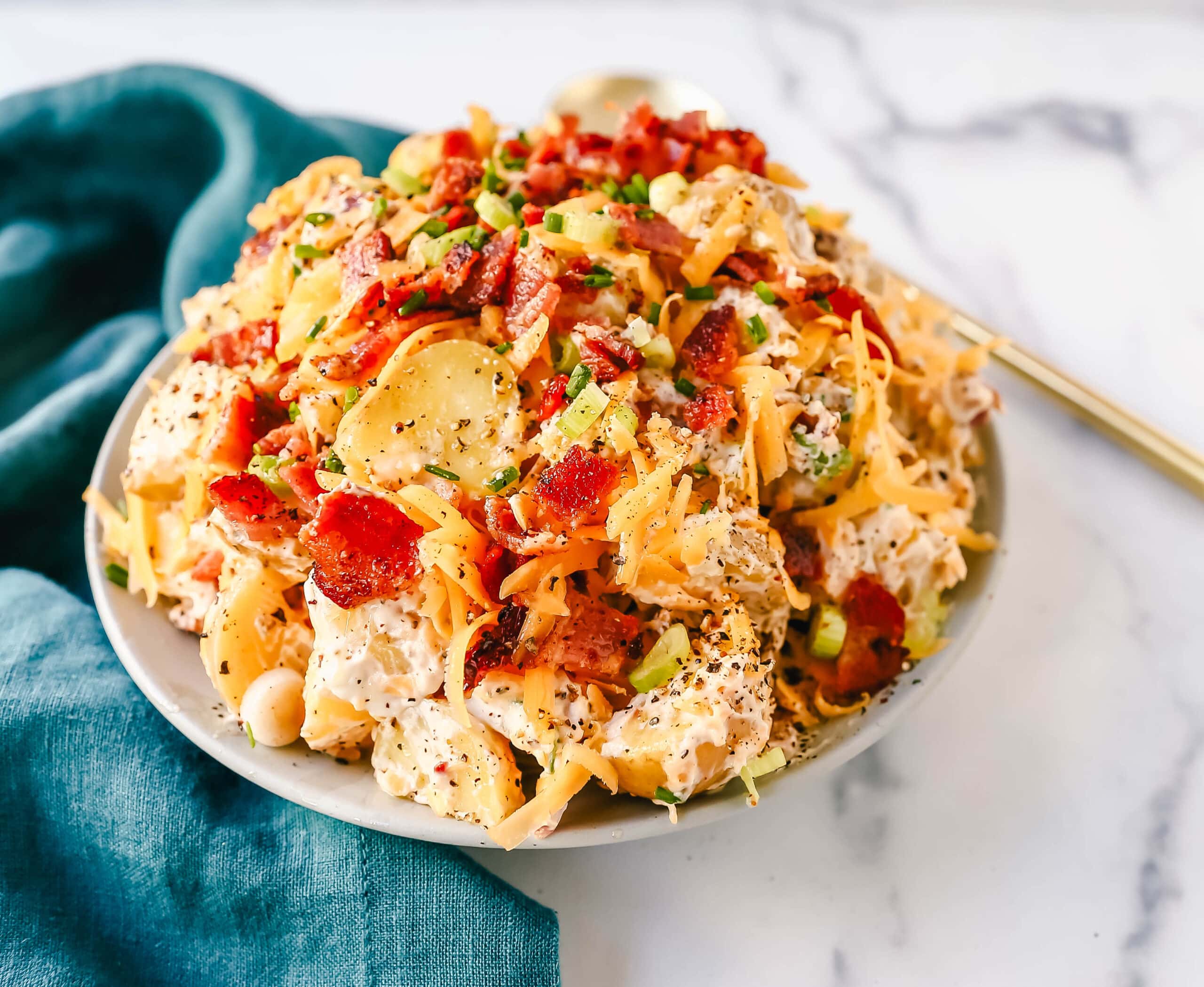 The Best Loaded Potato Salad Recipe is made with creamy gold potatoes, crispy bacon, cheddar cheese, green onions, sour cream, mayonnaise, seasoned salt, and pepper. The perfect baked potato salad recipe is perfect for your next party, potluck, or as a BBQ side dish.