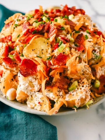 The Best Loaded Potato Salad Recipe is made with creamy gold potatoes, crispy bacon, cheddar cheese, green onions, sour cream, mayonnaise, seasoned salt, and pepper. The perfect baked potato salad recipe is perfect for your next party, potluck, or as a BBQ side dish.
