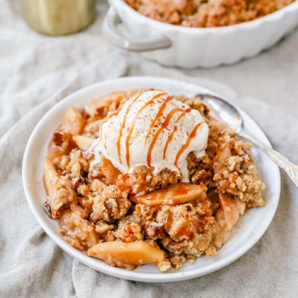 Homemade Apple Crumble Recipe made with fresh apples tossed in cinnamon sugar and topped with a brown sugar crumble made with butter, pecans, brown sugar, and flour. This apple crumble is baked until bubbly and topped with vanilla ice cream. An easy apple dessert!