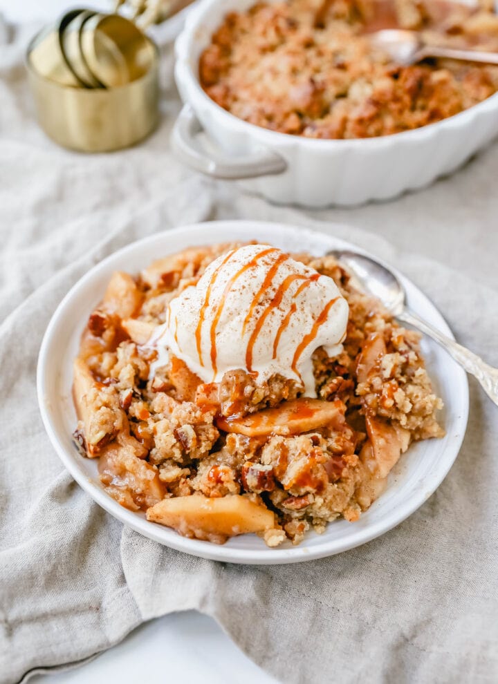 Homemade Apple Crumble Recipe made with fresh apples tossed in cinnamon sugar and topped with a brown sugar crumble made with butter, pecans, brown sugar, and flour. This apple crumble is baked until bubbly and topped with vanilla ice cream. An easy apple dessert!