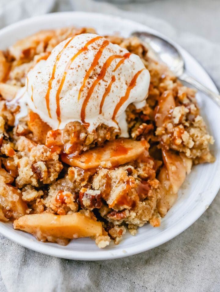 Homemade Apple Crumble Recipe made with fresh apples tossed in cinnamon sugar and topped with a brown sugar crumble made with butter, pecans, brown sugar, and flour. This apple crumble is baked until bubbly and topped with vanilla ice cream. An easy apple dessert!