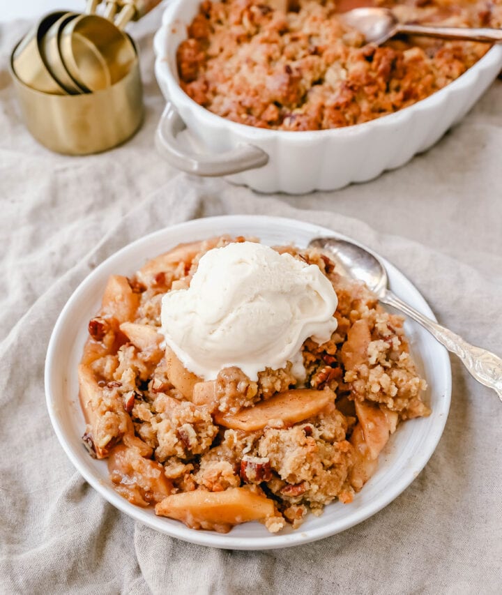 Homemade Apple Crumble Recipe made with fresh apples tossed in cinnamon sugar and topped with a brown sugar crumble made with butter, pecans, brown sugar, and flour. This apple crumble is baked until bubbly and topped with vanilla ice cream. An easy apple dessert!