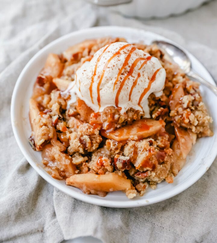 Homemade Apple Crumble Recipe made with fresh apples tossed in cinnamon sugar and topped with a brown sugar crumble made with butter, pecans, brown sugar, and flour. This apple crumble is baked until bubbly and topped with vanilla ice cream. An easy apple dessert!