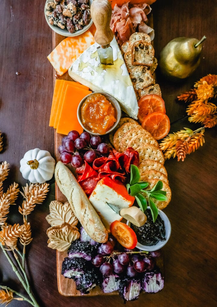 Festive Charcuterie Board perfect to celebrate Thanksgiving or Friendsgiving with friends and family. How to pick out the perfect meats, cheeses, fruits, jams, crackers, and dips for your Fall charcuterie spread. Tips and tricks for making the best charcuterie board.