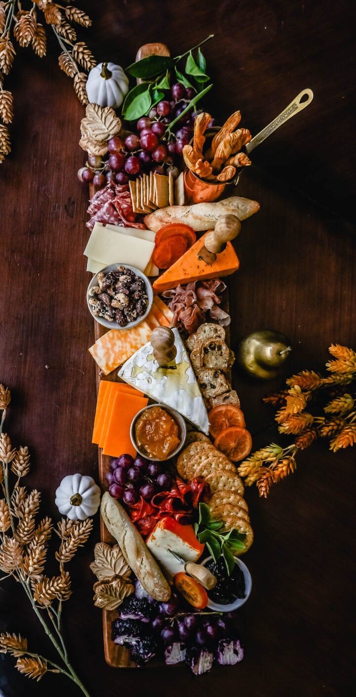 Festive Charcuterie Board perfect to celebrate Thanksgiving or Friendsgiving with friends and family. How to pick out the perfect meats, cheeses, fruits, jams, crackers, and dips for your Fall charcuterie spread. Tips and tricks for making the best charcuterie board.