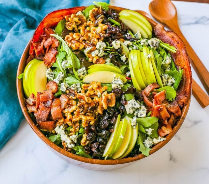 Fall Harvest Salad made with fresh apples, candied walnuts, dried cranberries, feta or blue cheese, crispy bacon all tossed with arugula or spring mix in a homemade apple cider vinegar dressing. The best Fall salad recipe!