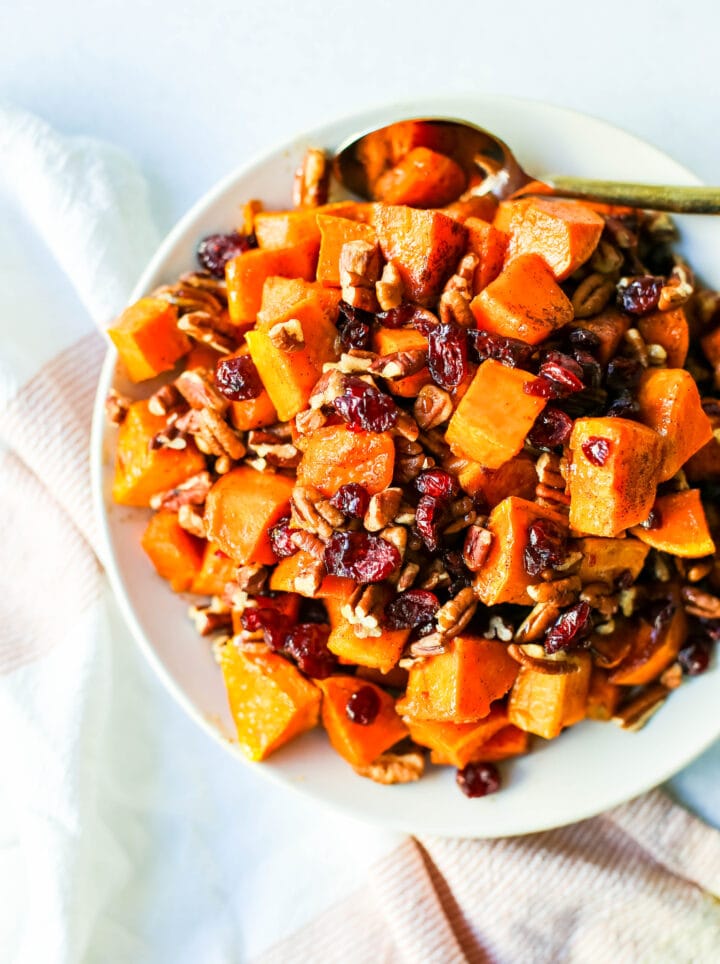 Roasted Sweet Potatoes with Cinnamon Maple Drizzle and tossed with dried cranberries and pecans. The perfect Fall side dish recipe! These roasted sweet potatoes make a beautiful Thanksgiving side dish. 