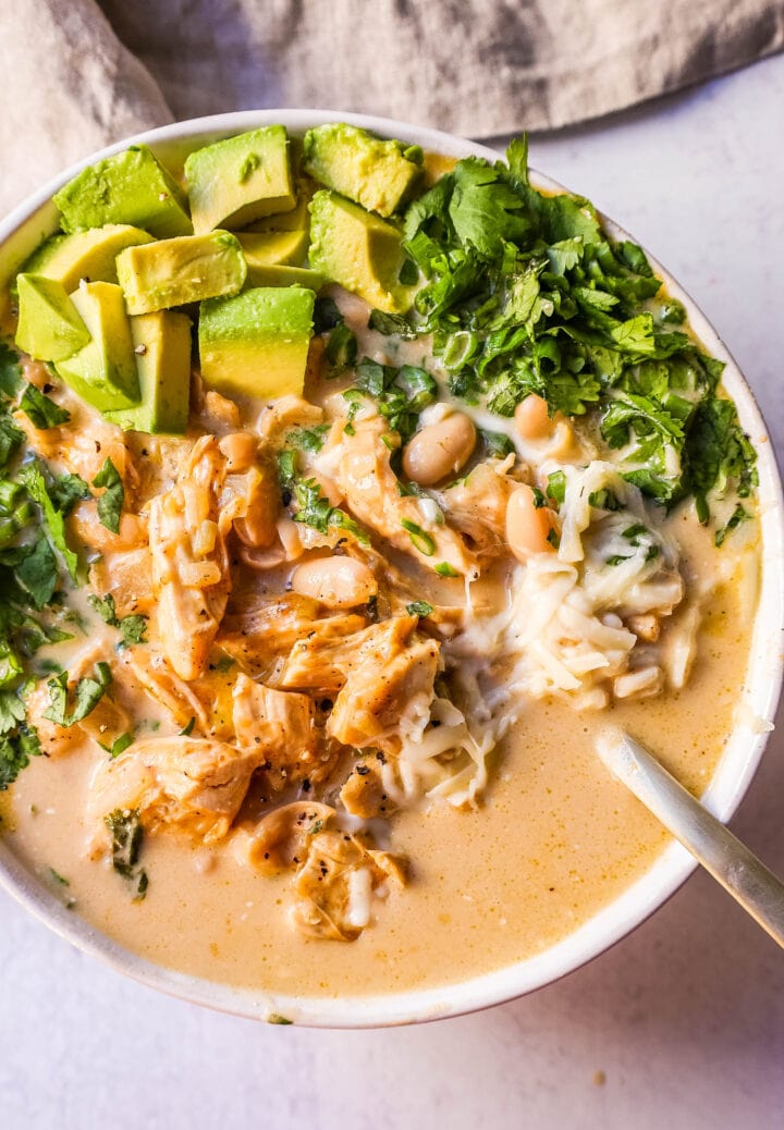 The Best White Chicken Chili Recipe made with shredded chicken, jalapeno, onion, spices, in a creamy chicken broth with salsa verde, cream cheese, white beans, shredded cheese, and fresh cilantro. The perfect creamy white chicken chili recipe!