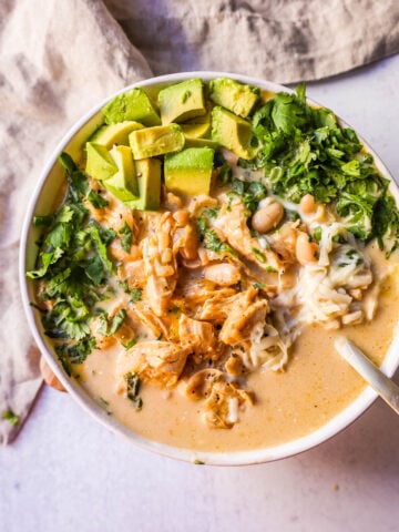 The Best White Chicken Chili Recipe made with shredded chicken, jalapeno, onion, spices, in a creamy chicken broth with salsa verde, cream cheese, white beans, shredded cheese, and fresh cilantro. The perfect creamy white chicken chili recipe!